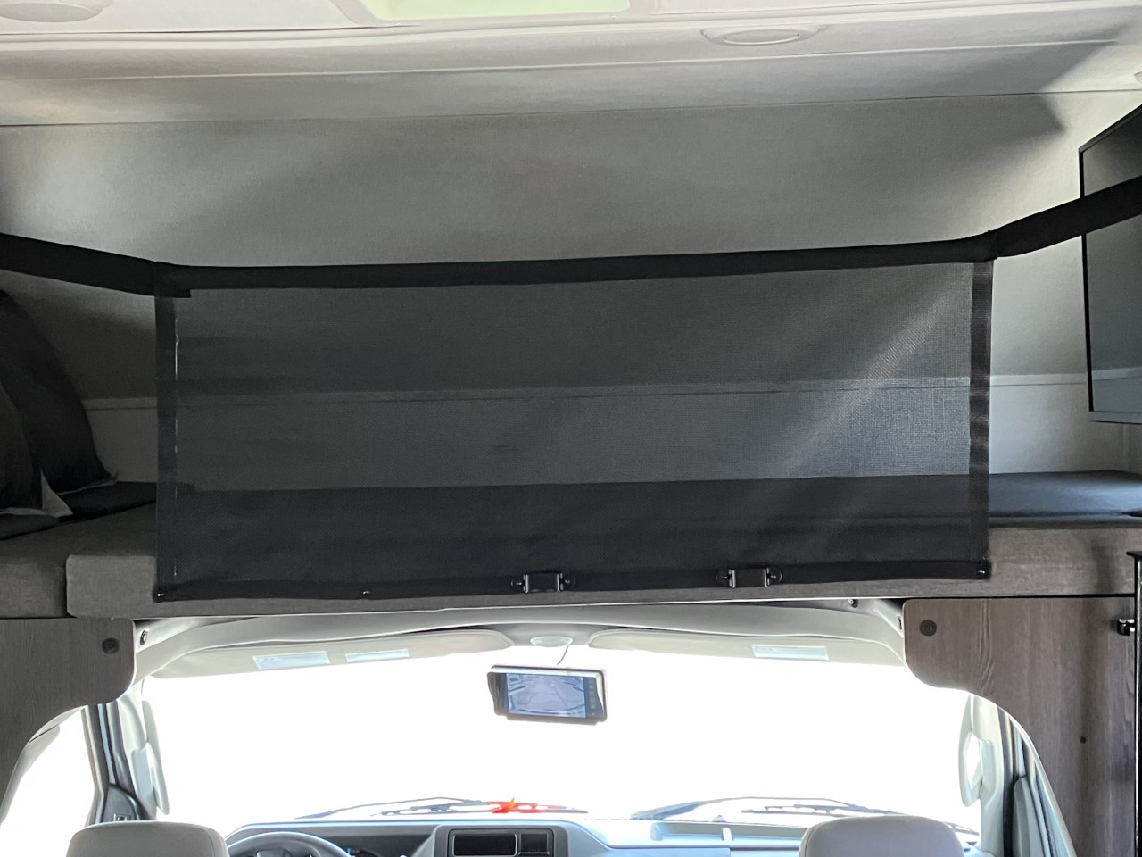 This rv rental interior features a cab-over bunk with a black mesh safety net, pillows, and a TV on the right.. Forest River Sunseeker LE 2022