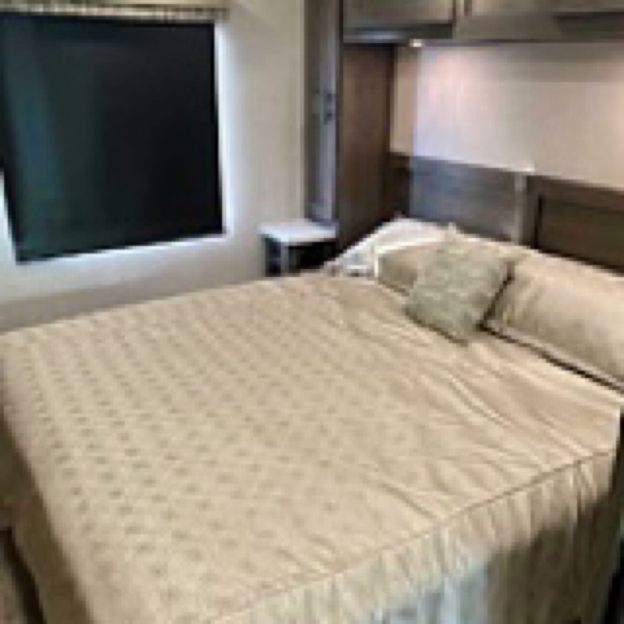 Enjoy this RV rental's comfy bedroom with a large bed, black blind, and storage cabinets.. Forest River Fr3 2021