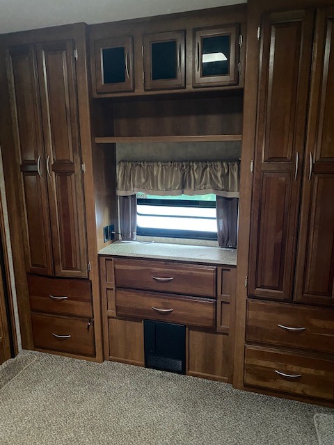 This RV rental interior features rich wood cabinets, drawers, and shelving for ample storage, centered around a window.. Crusader Crusader Fifth Wheel 2015