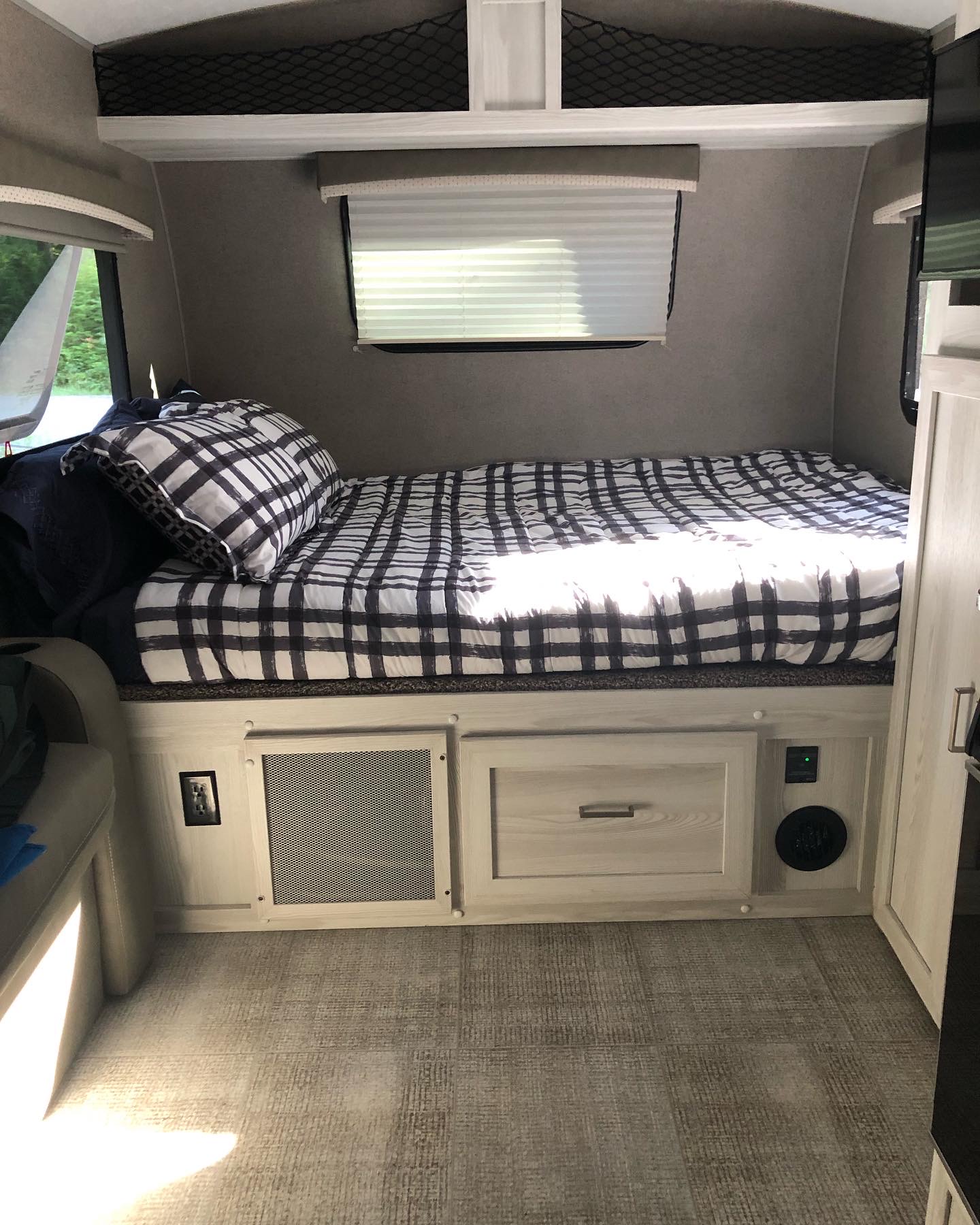 Cozy RV rental bedroom with black and white plaid bedding, a window, and light wood built-in storage cabinets.. Forest River Rockwood Geo Pro 2020