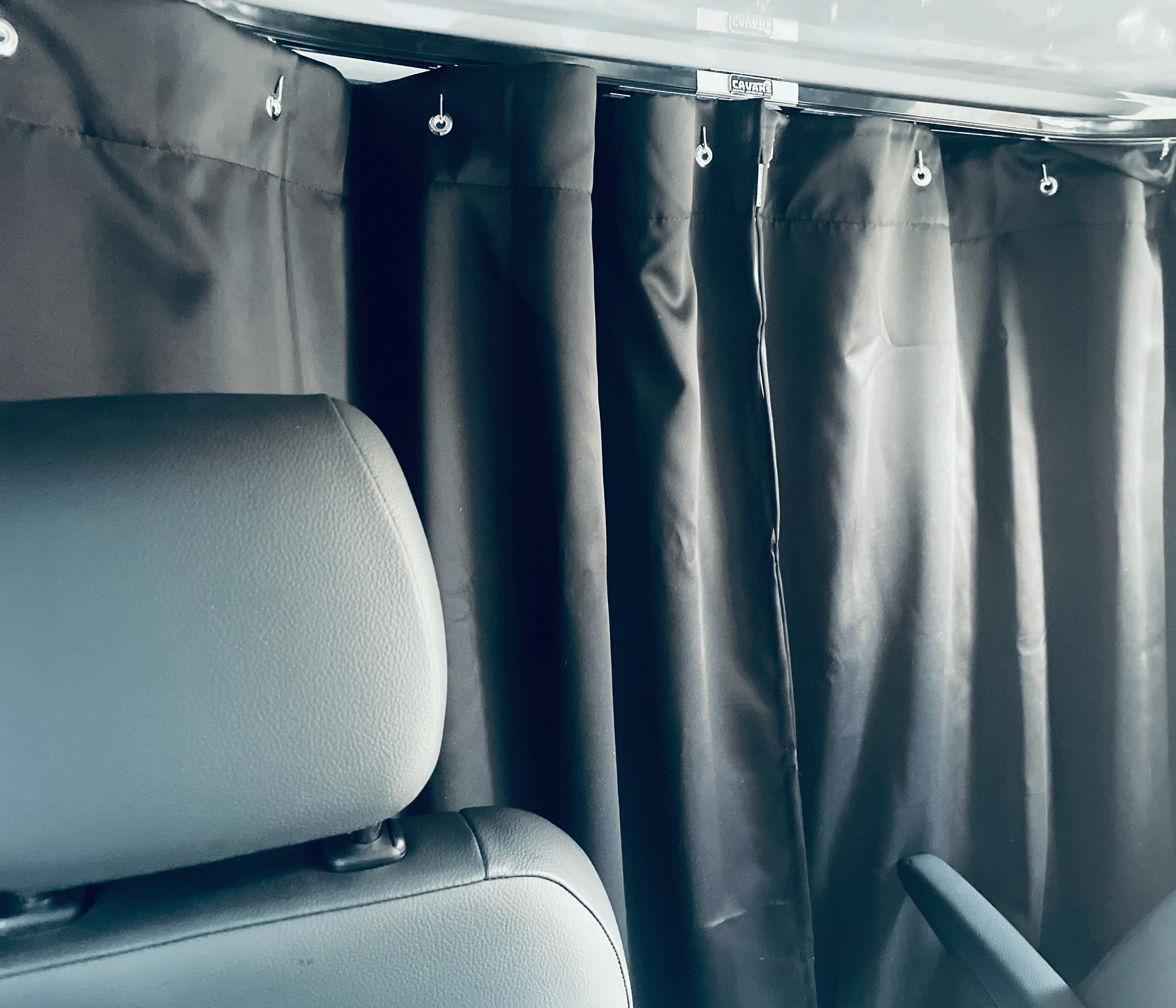 RV rental interior: black privacy curtains with CAVANS branding and passenger seat.. Winnebago Revel 2022