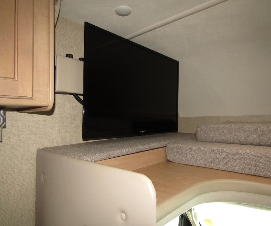 Modern RV rental interior with a wall-mounted TV and comfortable cushioned seating, perfect for travel entertainment.. Thor Motor Coach Freedom Elite 2019