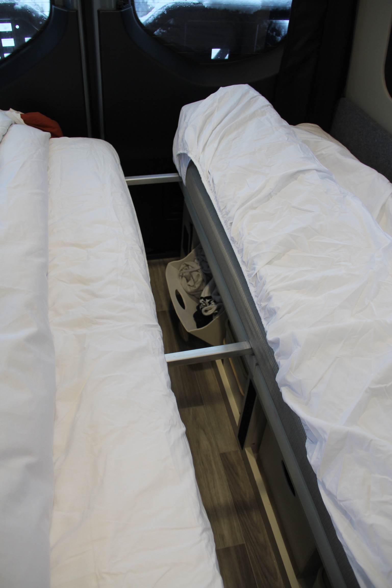 Two beds with white bedding in an RV rental, showcasing efficient interior space and accessible storage.. Mercedes Sprinter Van 2022