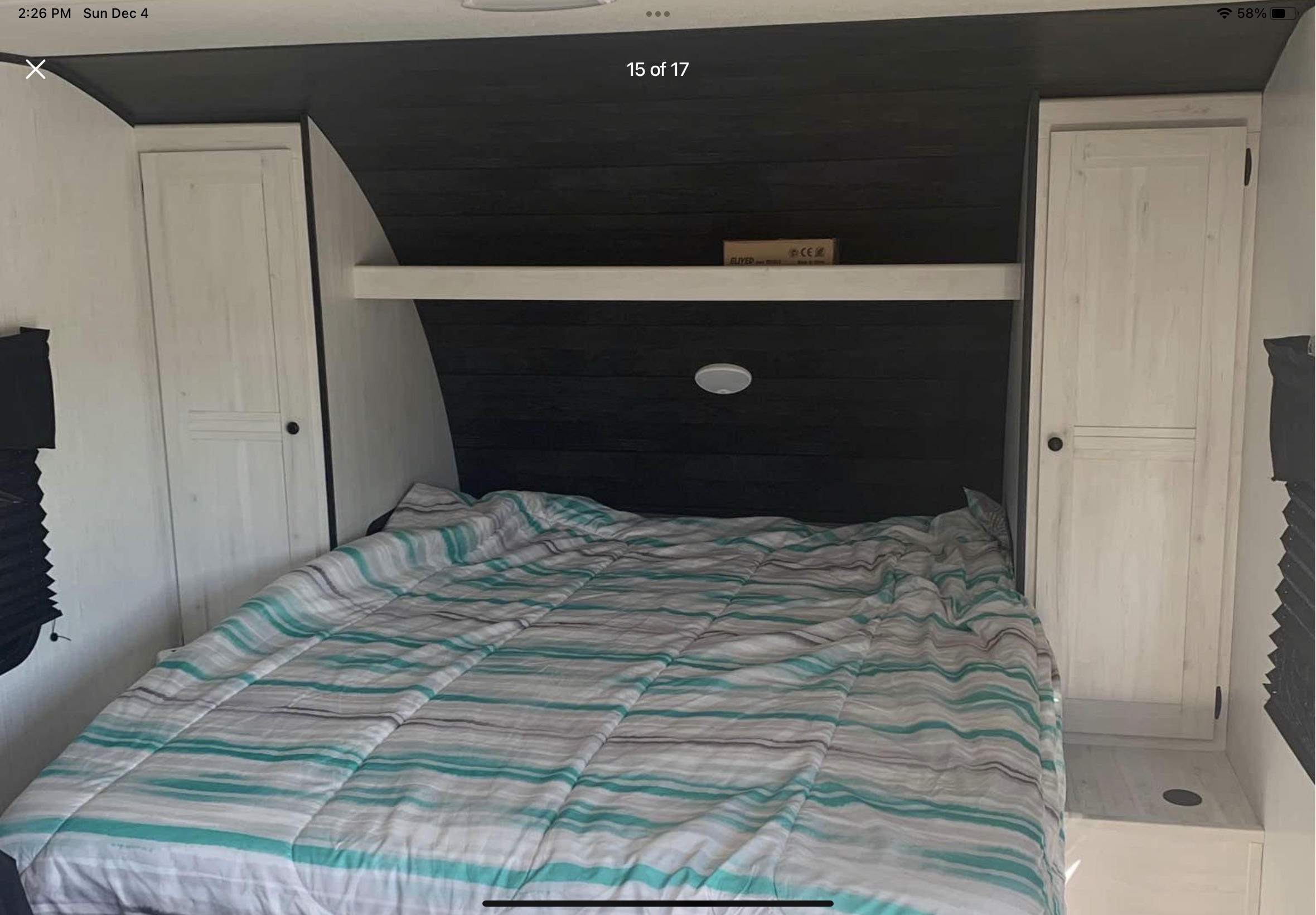 Cozy RV rental bedroom with striped comforter, built-in cabinets, and overhead shelf, ideal for comfortable travels.. Heartland RVs Trail Runner 2022