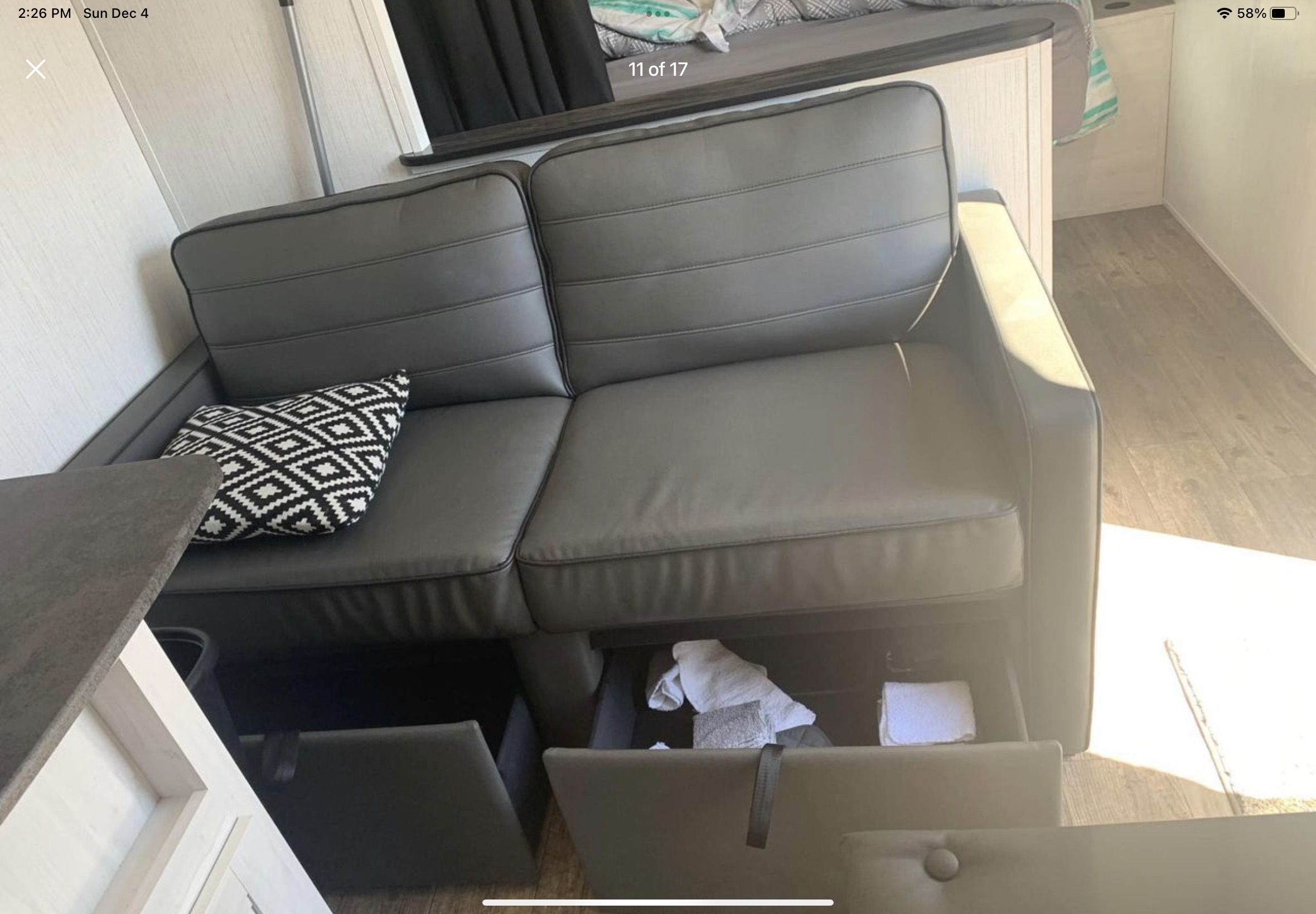 Modern gray sofa with under-seat storage and a patterned pillow inside an RV rental. Cozy living area.. Heartland RVs Trail Runner 2022