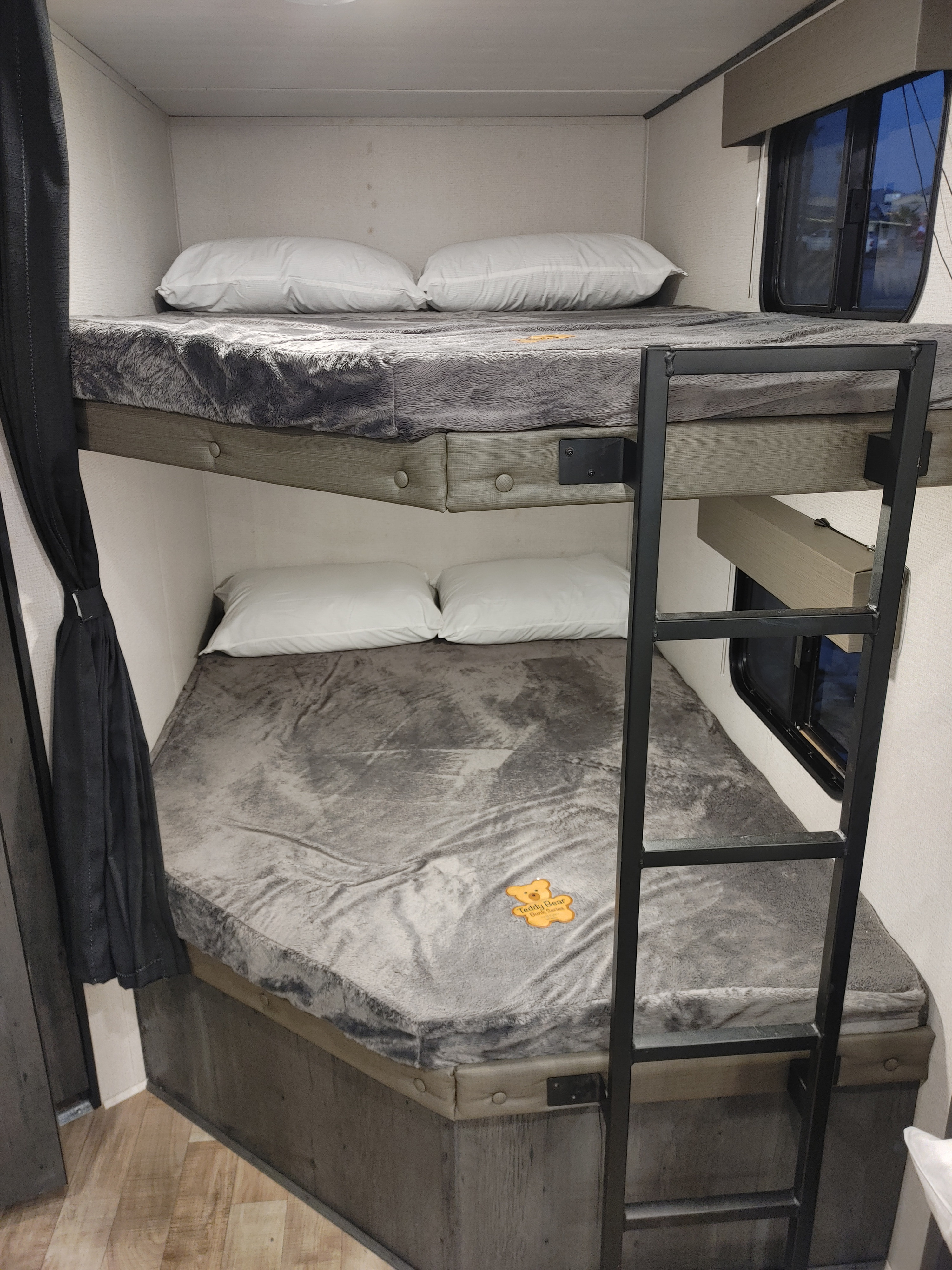 Cozy bunk beds in an rv rental, featuring gray blankets, white pillows, and a ladder for access to the top bunk.. Keystone RV Hideout 2022
