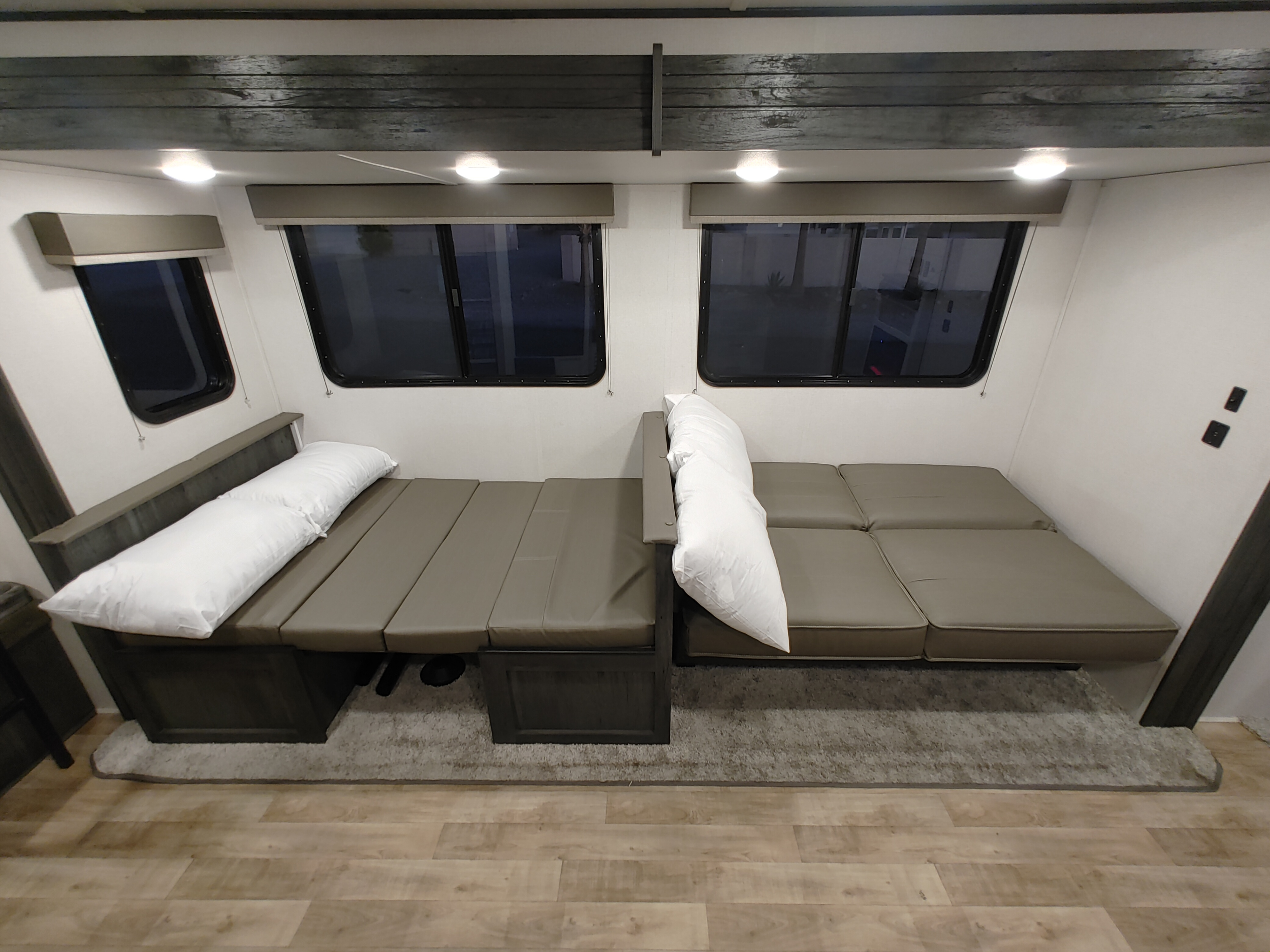 Spacious RV rental interior with two gray convertible sofa beds under windows, providing flexible seating & sleeping.. Keystone RV Hideout 2022