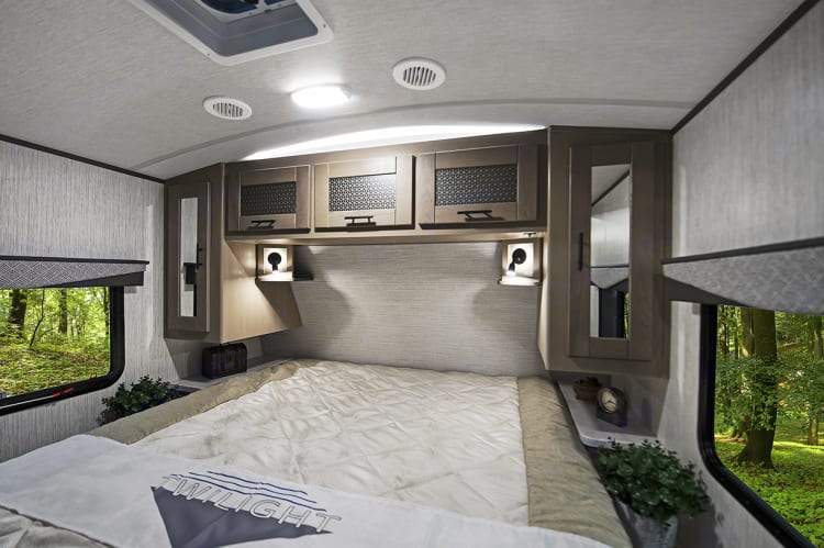 Inside a comfortable **rv rental** bedroom featuring a cozy bed, overhead storage, and scenic window views.. Twilight RVS Signature 2021