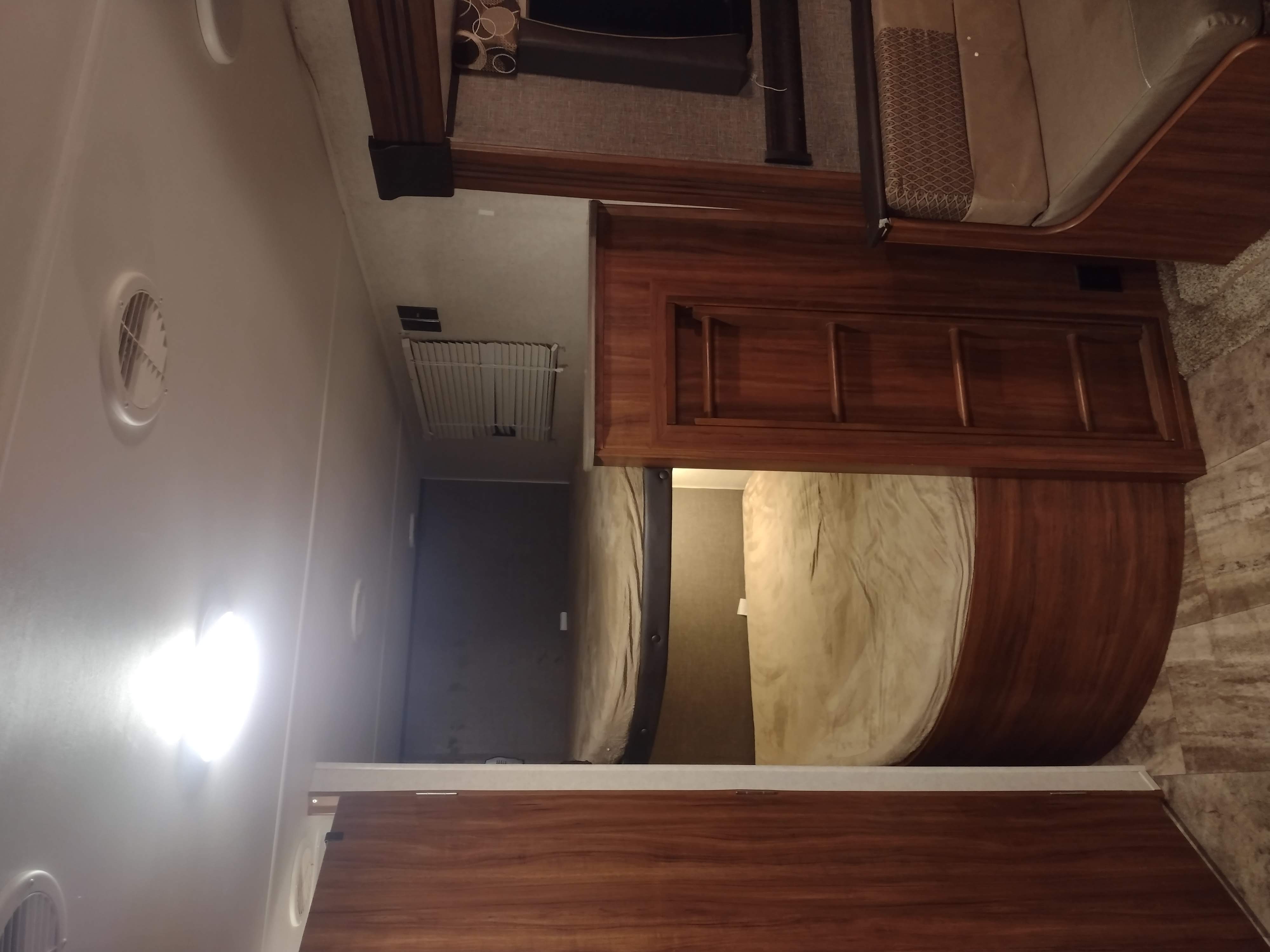 Comfortable RV rental bedroom interior, featuring wooden cabinetry, a plush bed, and ceiling vents.. Heartland Trail Runner 2016