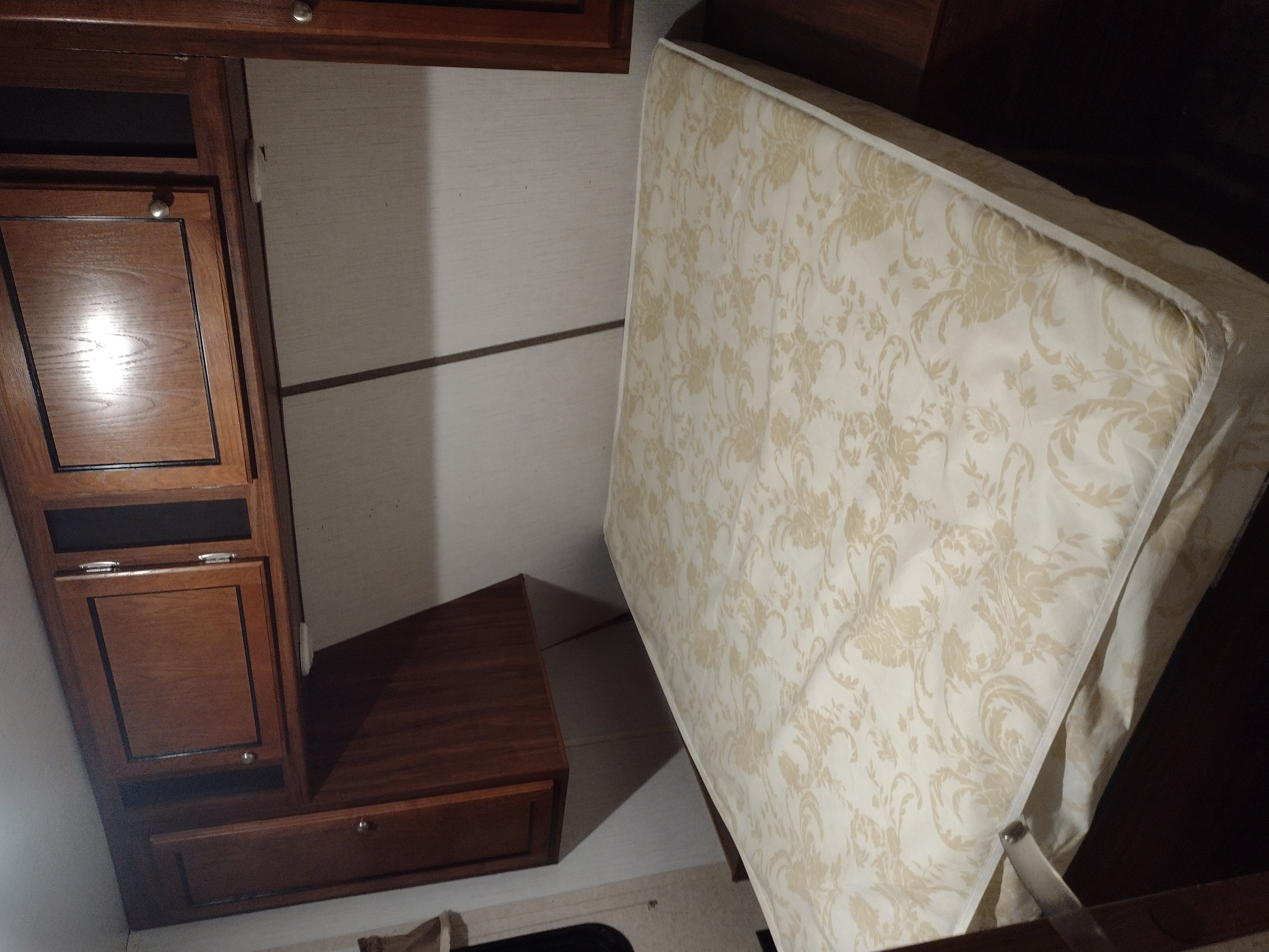 RV rental interior: lifted mattress for storage access, with wooden cabinets and compact design.. Heartland Trail Runner 2016
