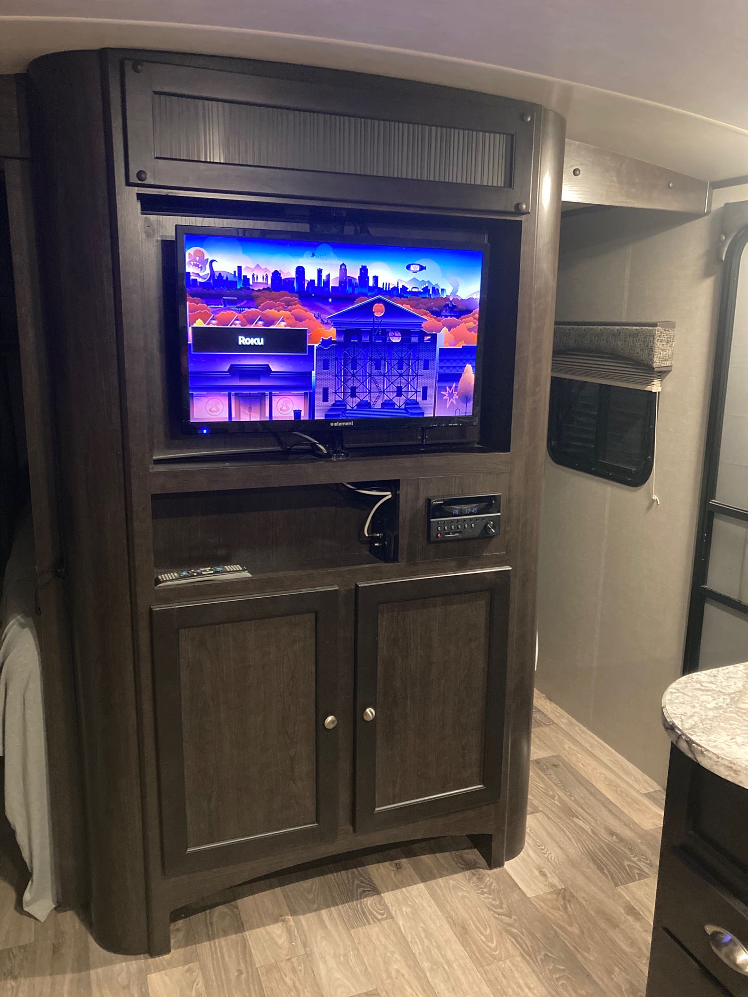 RV rental living space: Dark wood entertainment center with TV, audio unit, storage, and a partial view of the bed.. Heartland RVs Sundance XLT 2017
