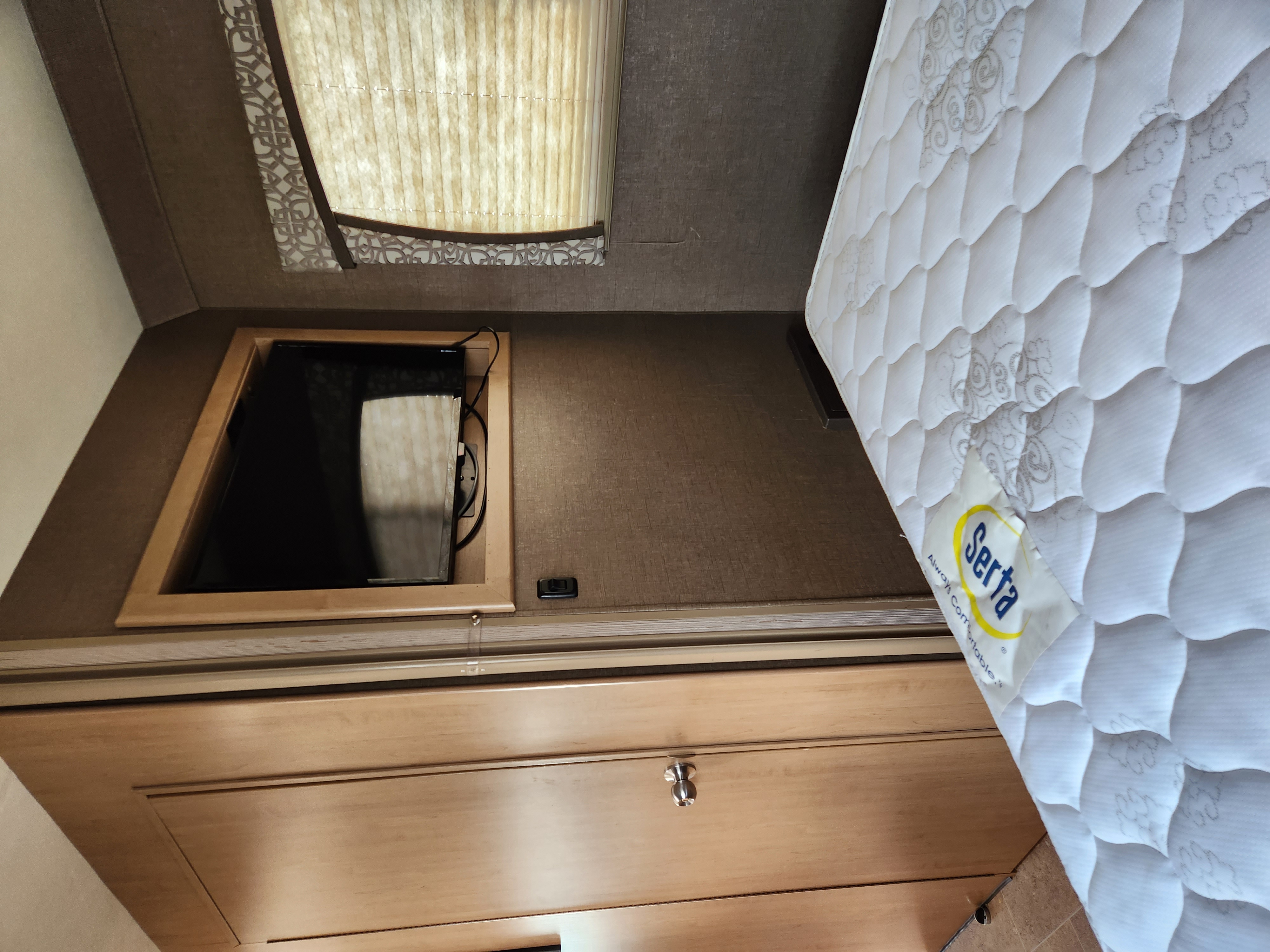 Explore this cozy RV rental interior: Serta mattress, wall-mounted TV, window blinds, and wood cabinetry.. Thor Chateau 2019