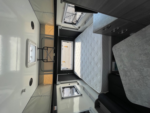 This rv rental offers a well-lit interior with a large bed, dinette, and several windows.. OBI Dweller13 2022