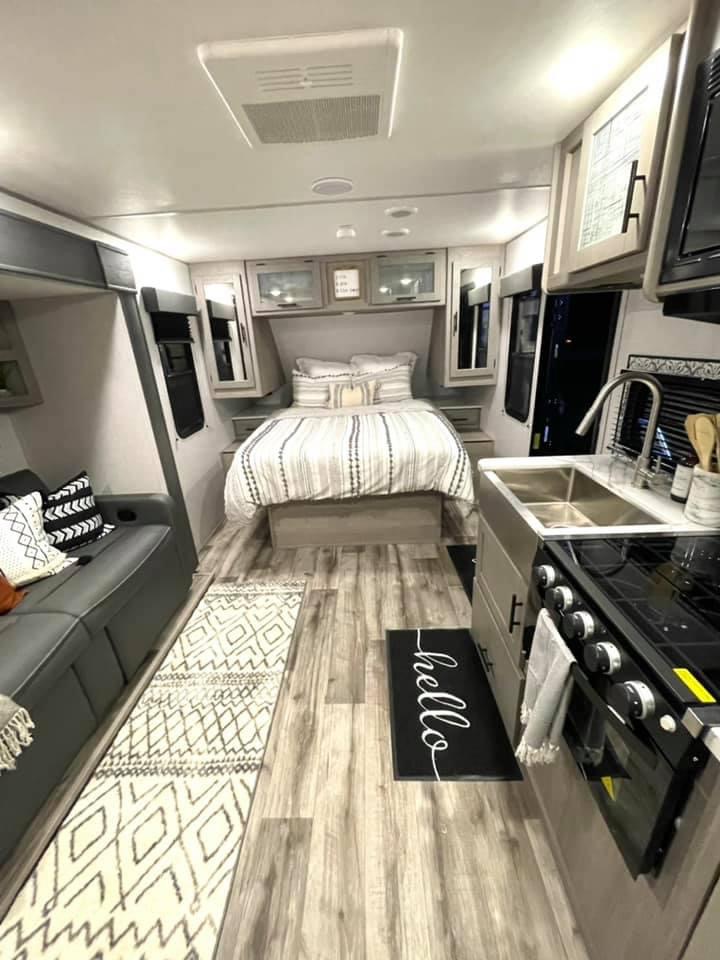 Discover this clean RV rental interior, featuring a cozy bedroom, well-equipped kitchen, and lounge area.. Dutchmen Coleman Light 2022
