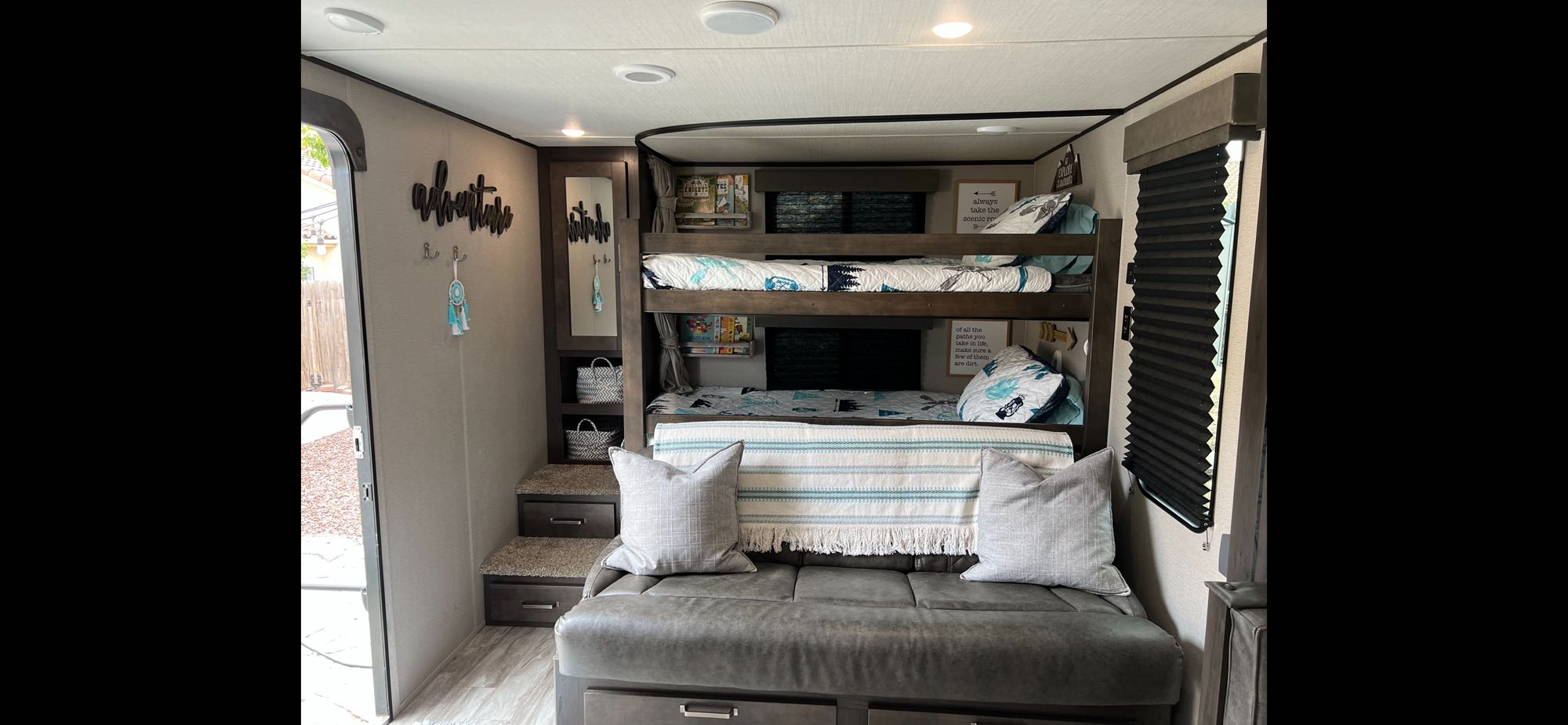 This RV rental bunkhouse features cozy bunk beds, a comfy sofa, and adventure-themed decor for family fun.. Grand Design Transcend Xplor 2021