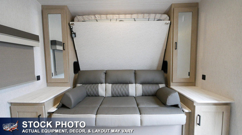 RV rental interior: A modern grey sofa, a fold-up Murphy bed, and storage cabinets in a compact living area.. Forest River Impression 2020