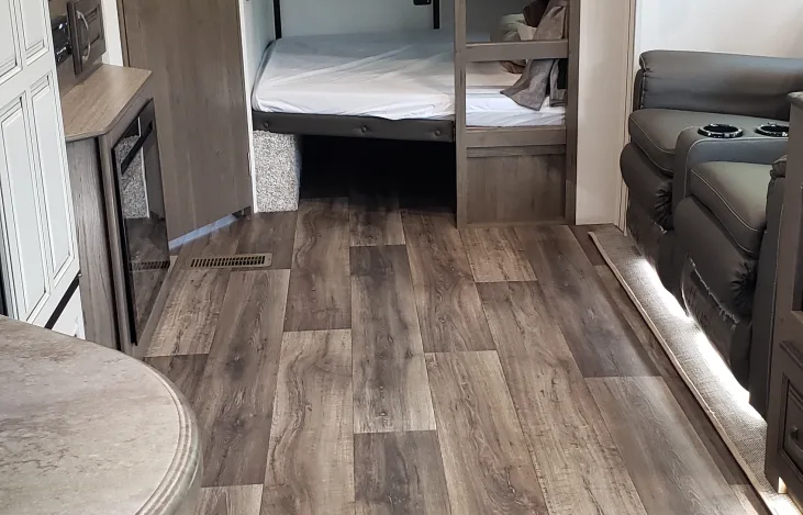 RV rental interior: Wood-look flooring, cozy bunk beds, and reclining seats offer comfort for travel.. Keystone RV Cougar 2021