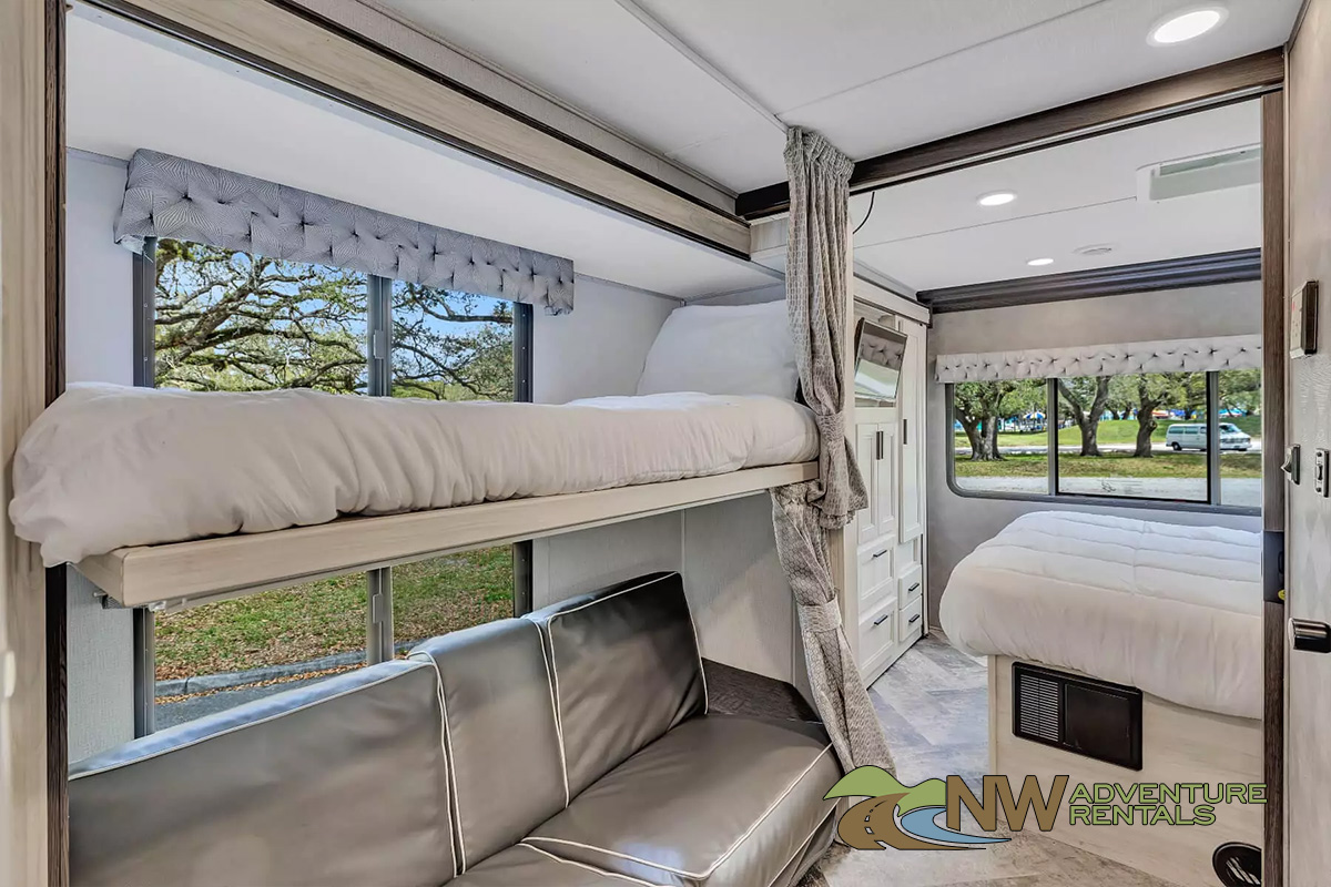 Cozy RV rental interior with bunk beds, a sofa, and main bed. Ideal for family adventures & comfortable travel.. Forest River Sunseeker 2022