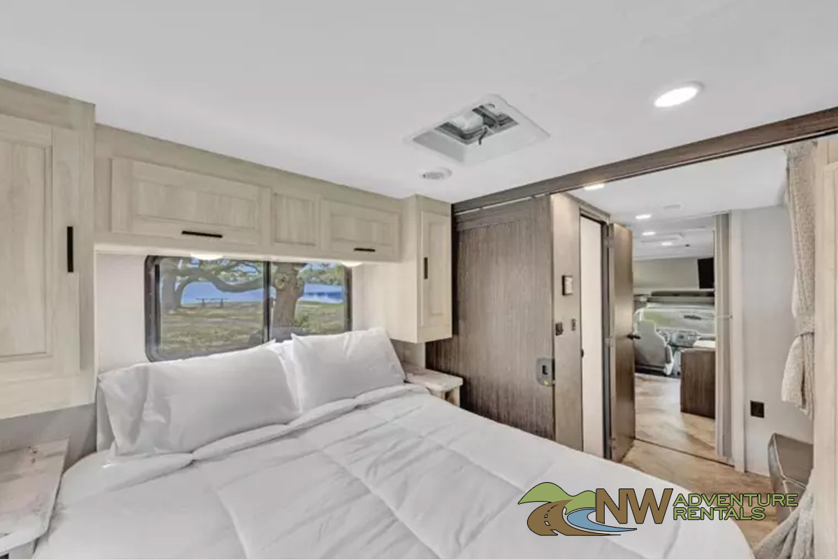 Spacious RV rental bedroom with comfortable bed, overhead storage, and a scenic window view. Perfect for your next adventure!. Forest River Sunseeker 2022