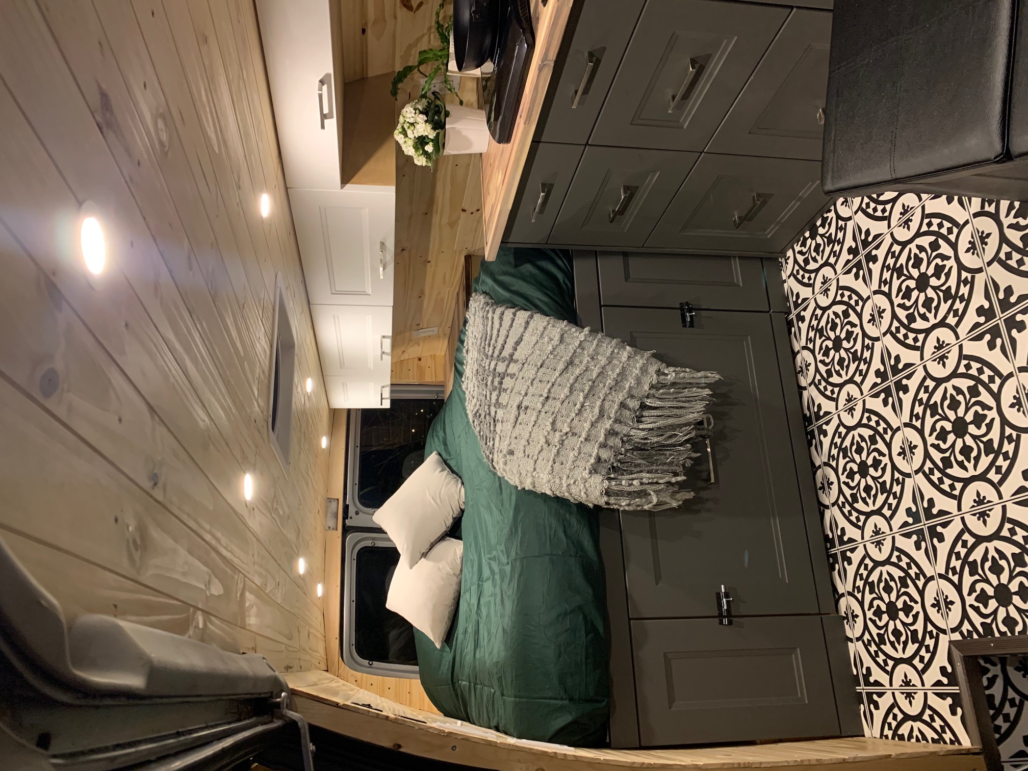 This RV rental's cozy interior features wood panels, modern cabinets, patterned floor, and a comfortable bed.. Ford Econoline 2009
