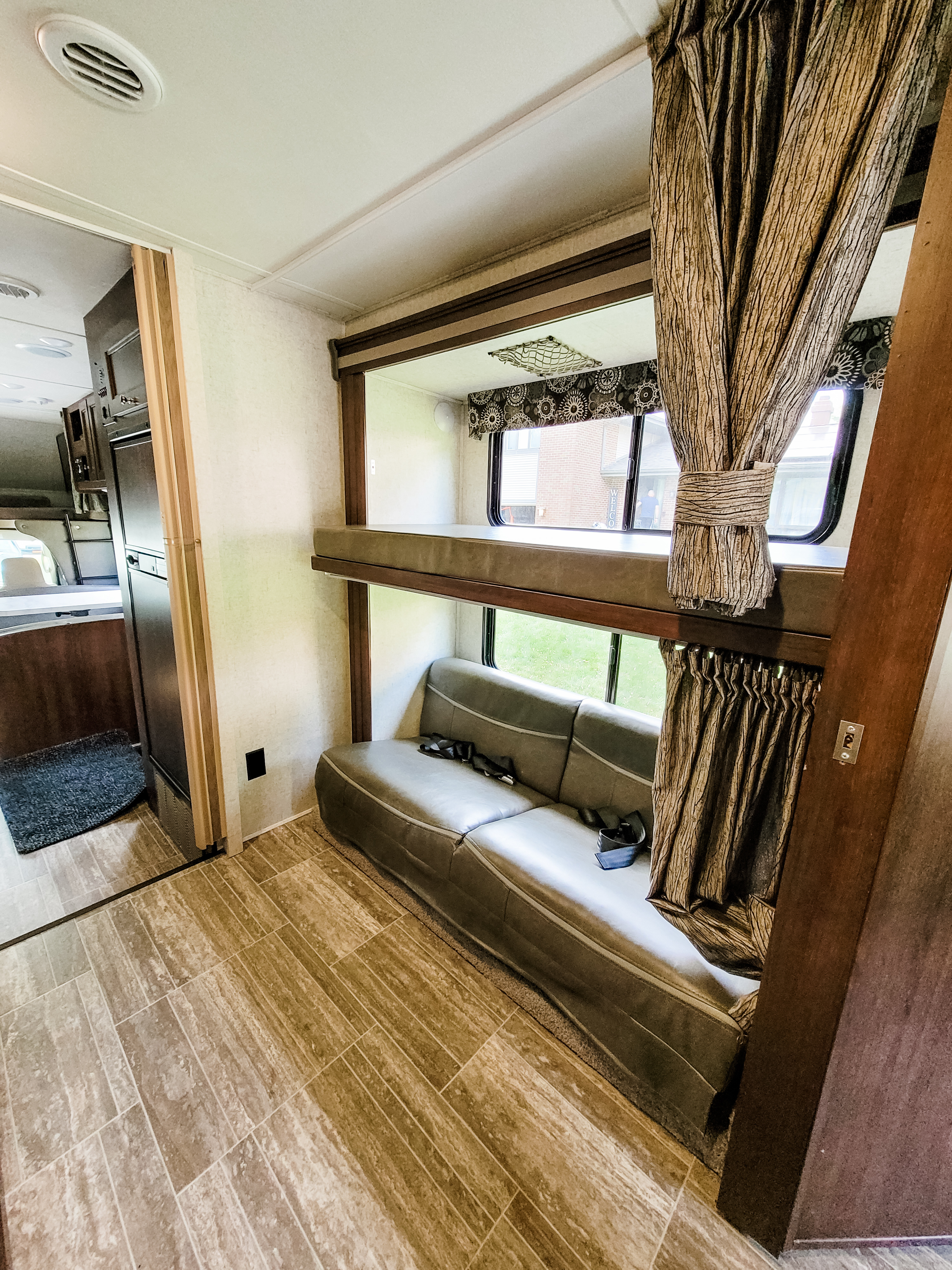 RV rental interior: cozy living space with bunk beds, couch, and light tiled flooring.. Forest River Sunseeker LE 2018