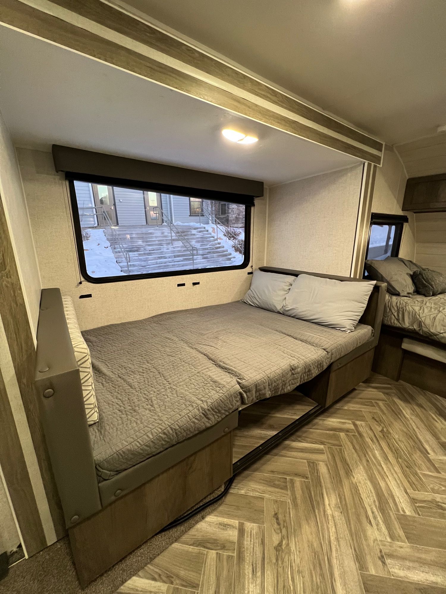 This RV rental's bedroom shows a comfortable pull-out bed, an adjacent bed, and a large window with a snowy outdoor view.. Forest River Other 2021