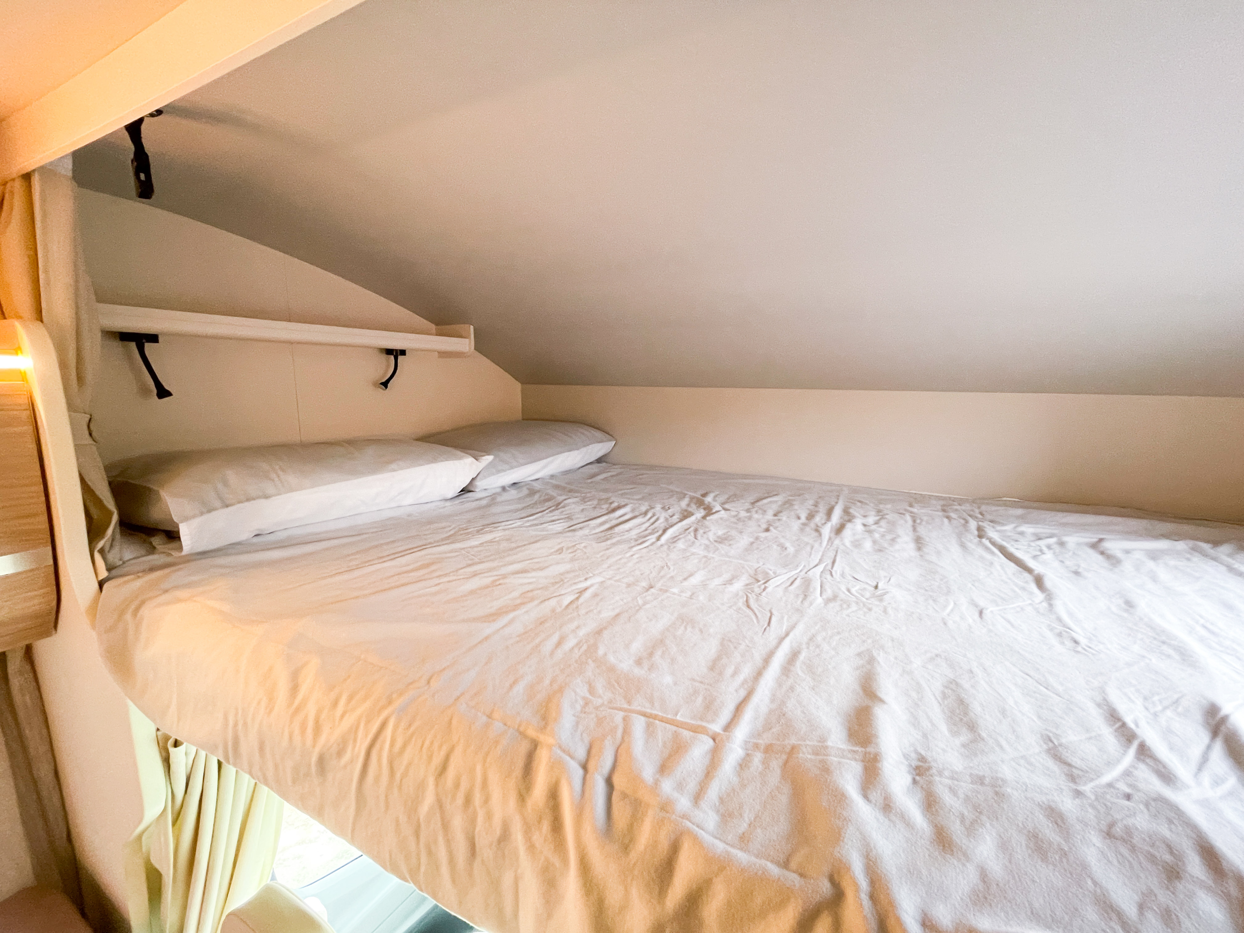Cozy RV rental sleeping area featuring a comfortable bed with white sheets and pillows, ideal for a restful night.. MUNRO MUNRO 2022