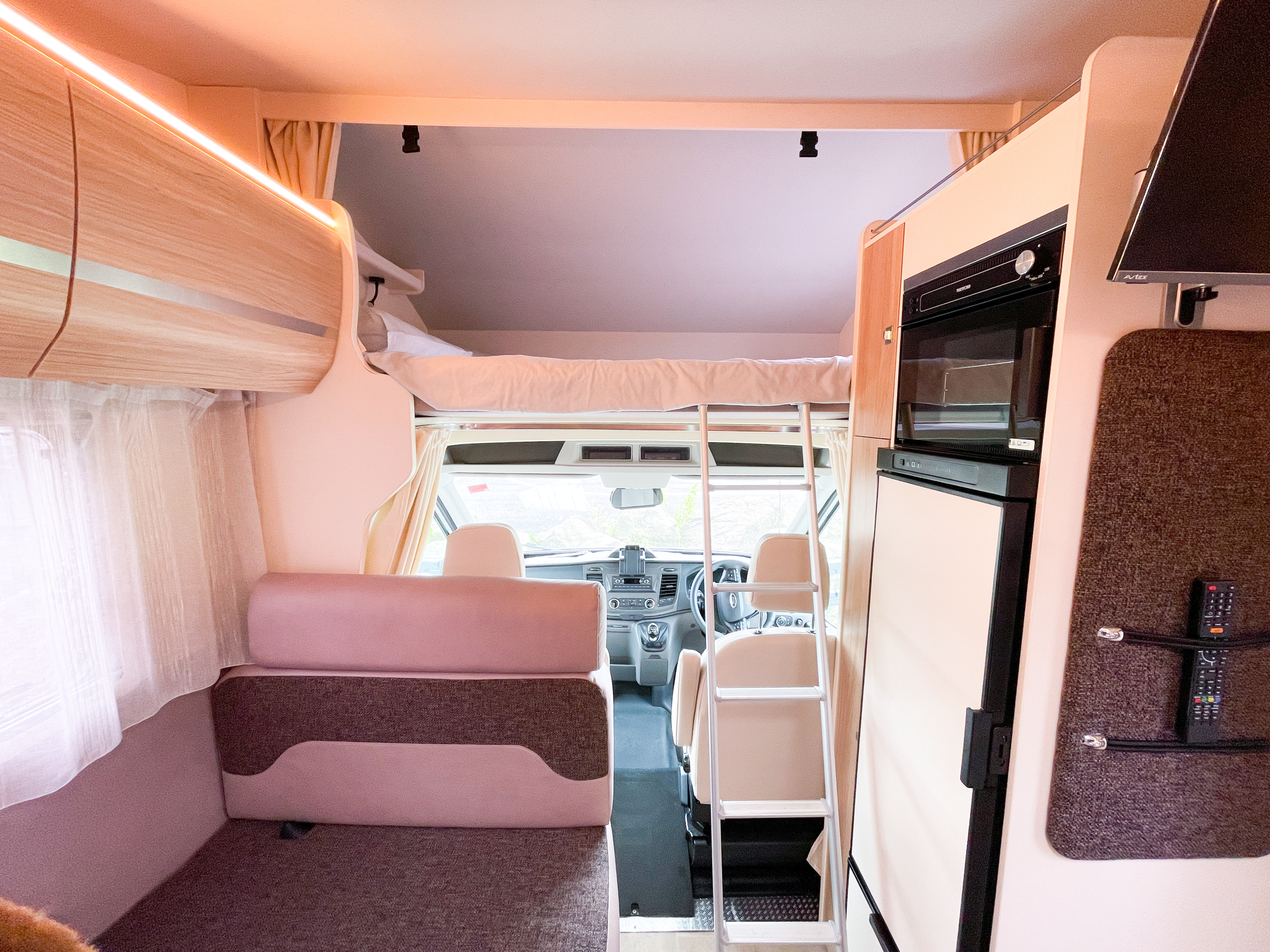 Spacious RV rental interior featuring an overcab bunk, comfortable lounge area, and a fully equipped kitchen. Ideal for road trips.. MUNRO MUNRO 2022