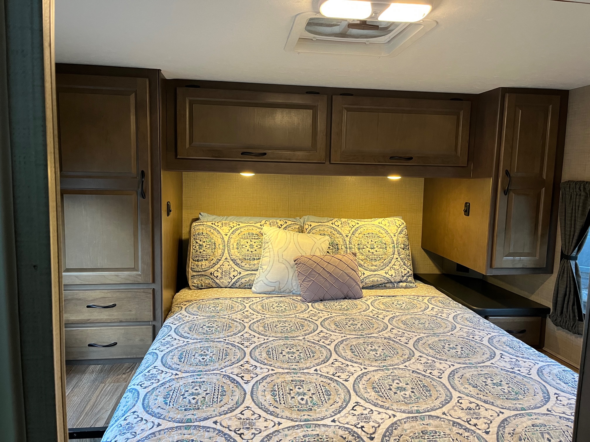 Comfortable RV rental bedroom with a large bed, ample storage cabinetry, and ceiling lights, ideal for travel.. Thor Majestic 2018