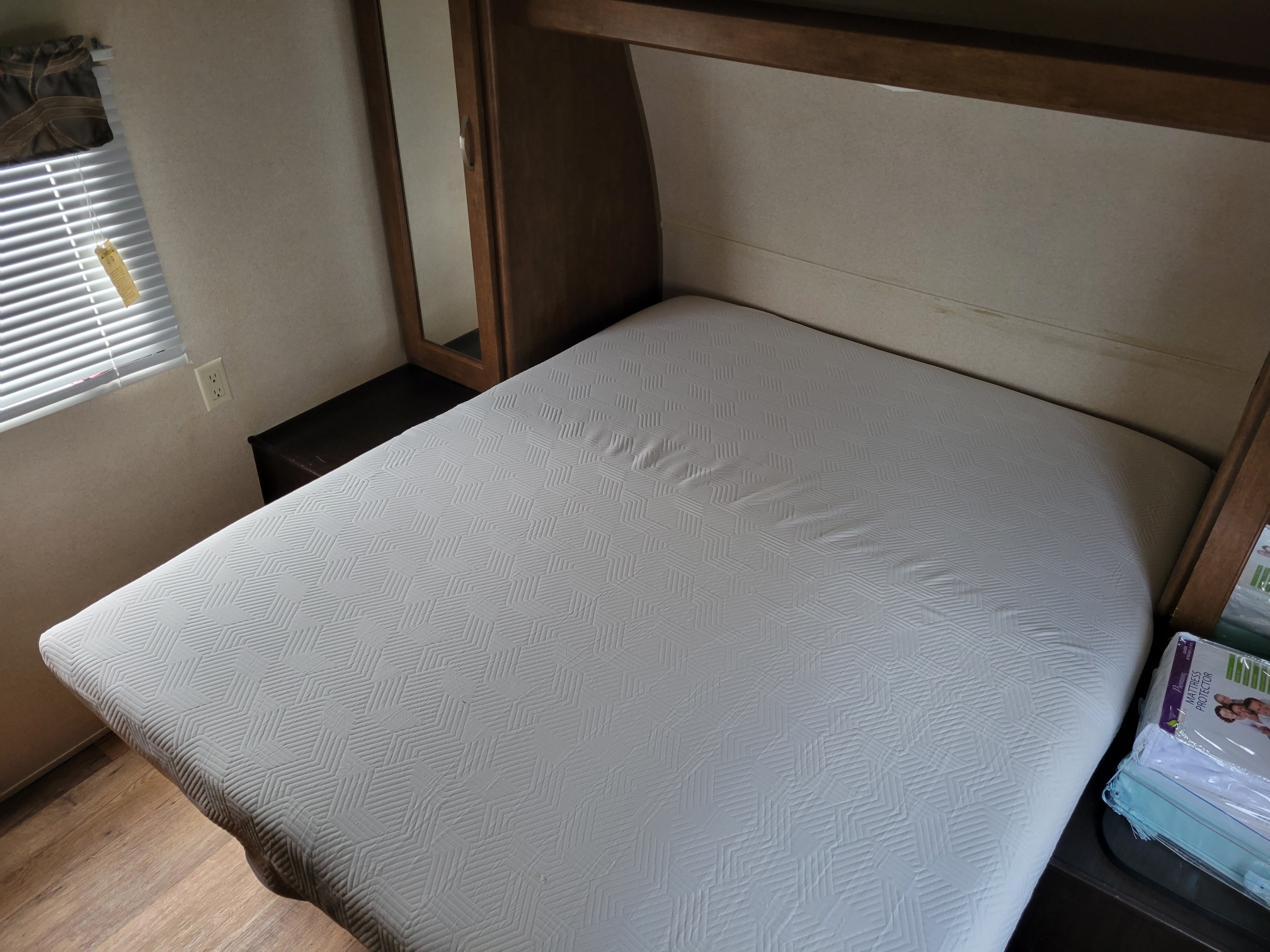 Cozy RV rental bedroom with a fresh bed, mattress protector, window, and built-in storage.. Forest River Wildwood 2018