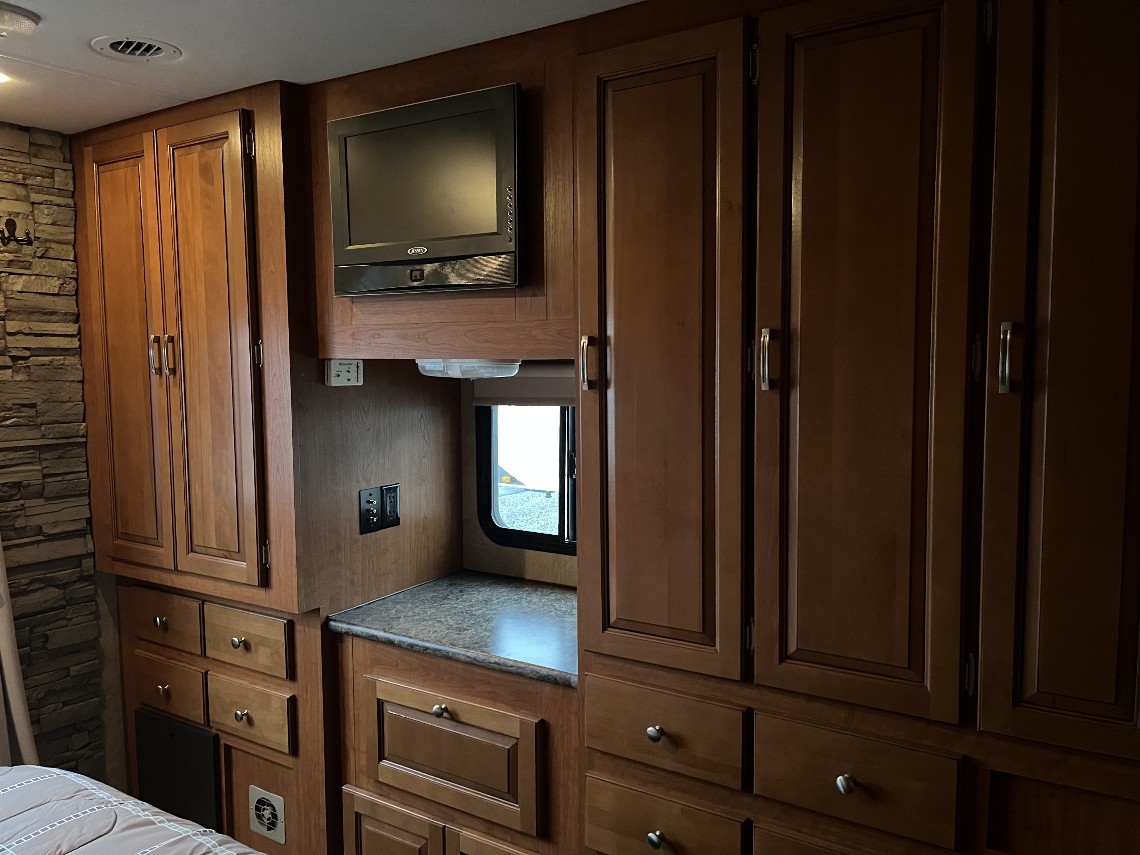 Inside this RV rental: bedroom area featuring a wall-mounted TV, numerous wood cabinets & drawers, plus a window.. Forest River Georgetown M373DS 2011