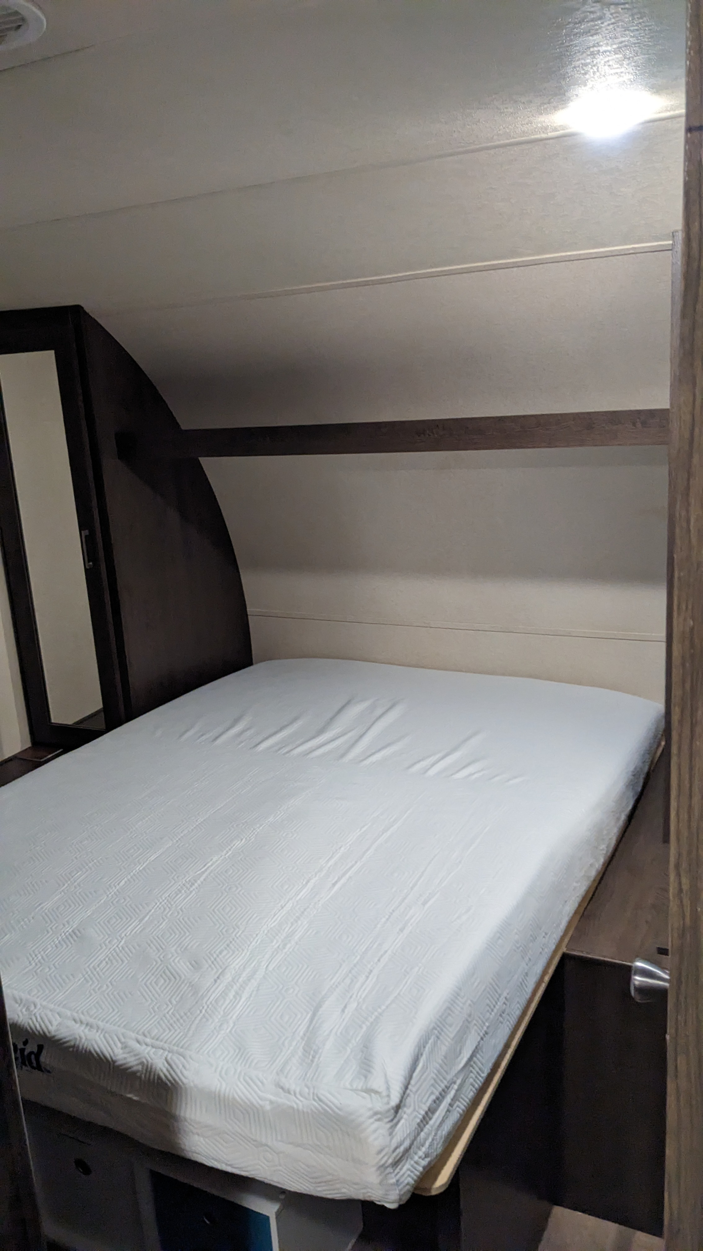 Cozy RV rental bedroom with a bed, wardrobe, and overhead shelf, offering a compact and functional sleeping space.. Forest River Salem 2018