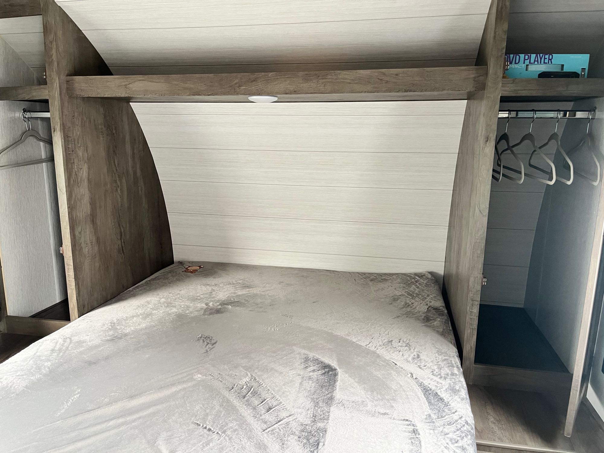 Bright RV rental bedroom: cozy bed with built-in storage wardrobes and overhead lighting.. Forest River Wildwood X-Lite 2022