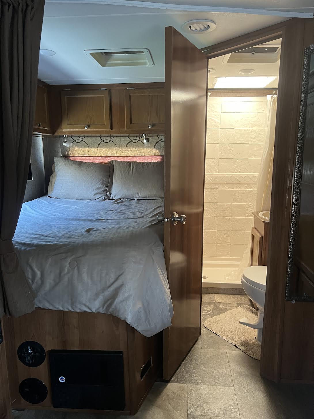 RV rental interior: A cozy bedroom with bed and overhead storage, leading to a compact bathroom with shower and toilet.. Other Other 2018