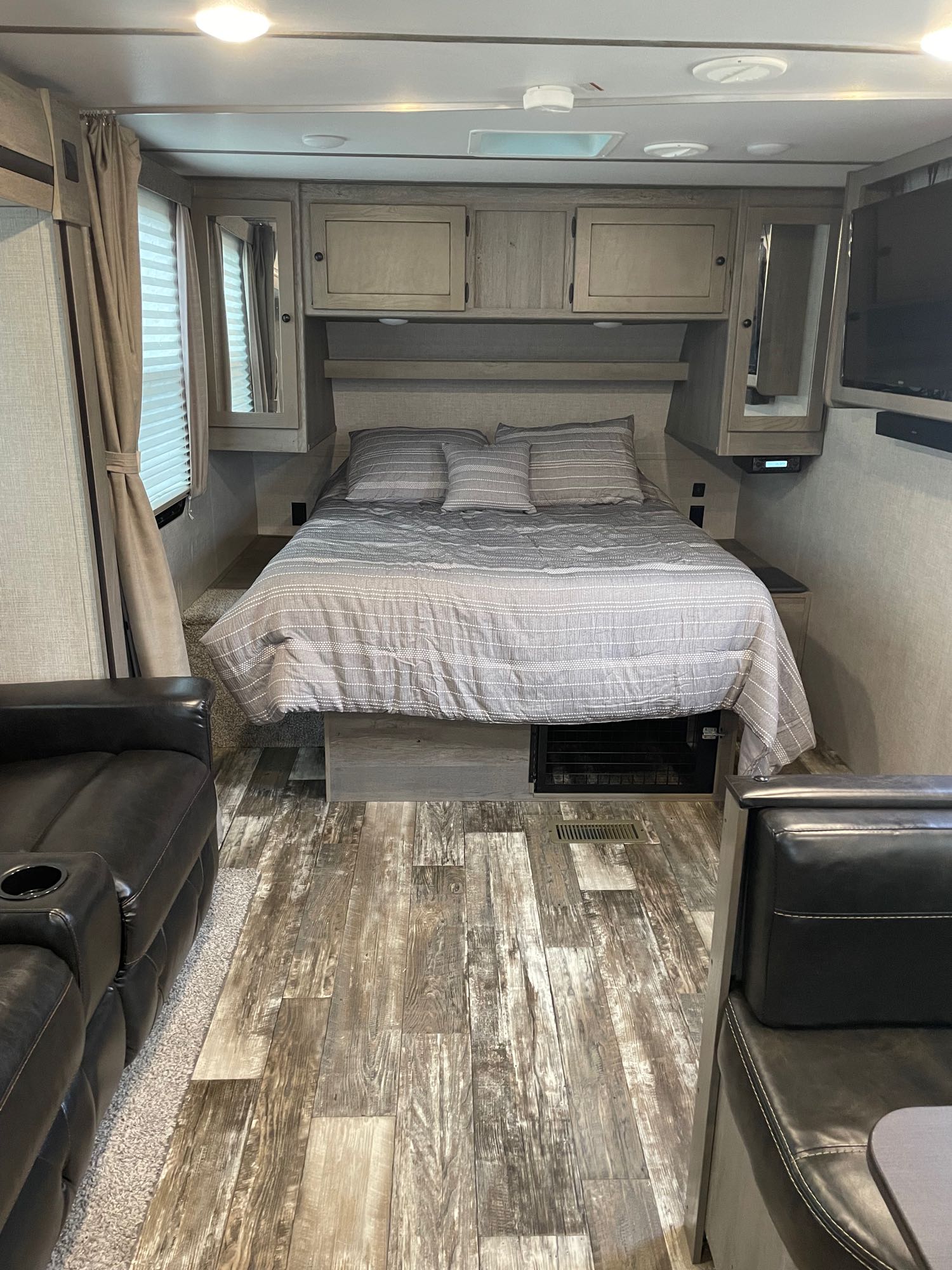 An RV rental's compact bedroom and living area, with a comfy bed, sofa, and overhead storage, ready for your next trip.. Keystone RV Outback Ultra-Lite 2019