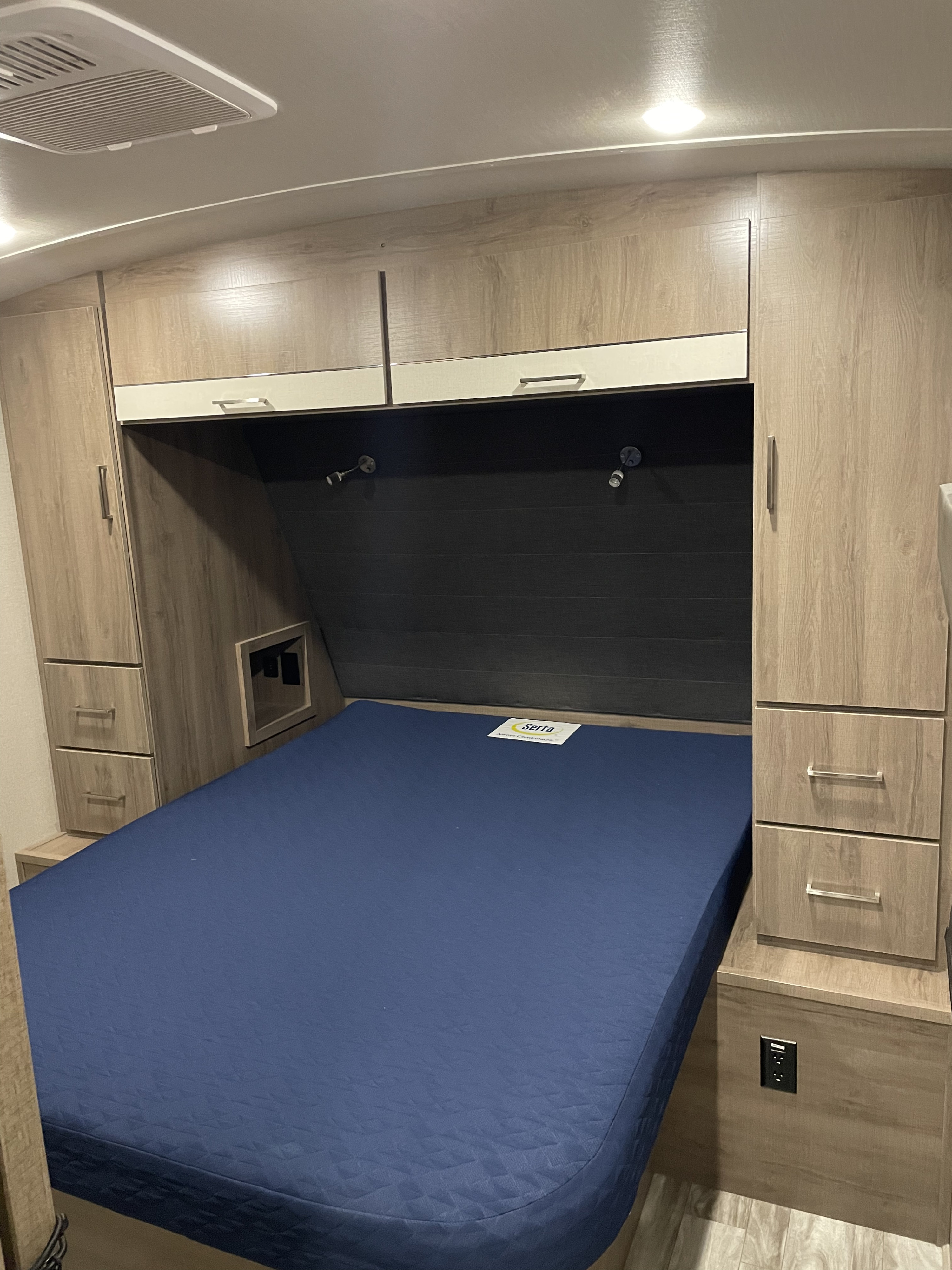 Cozy RV rental bedroom with a Serta mattress, built-in storage, and reading lights, perfect for travel comfort.. Grand Design Imagine 2022