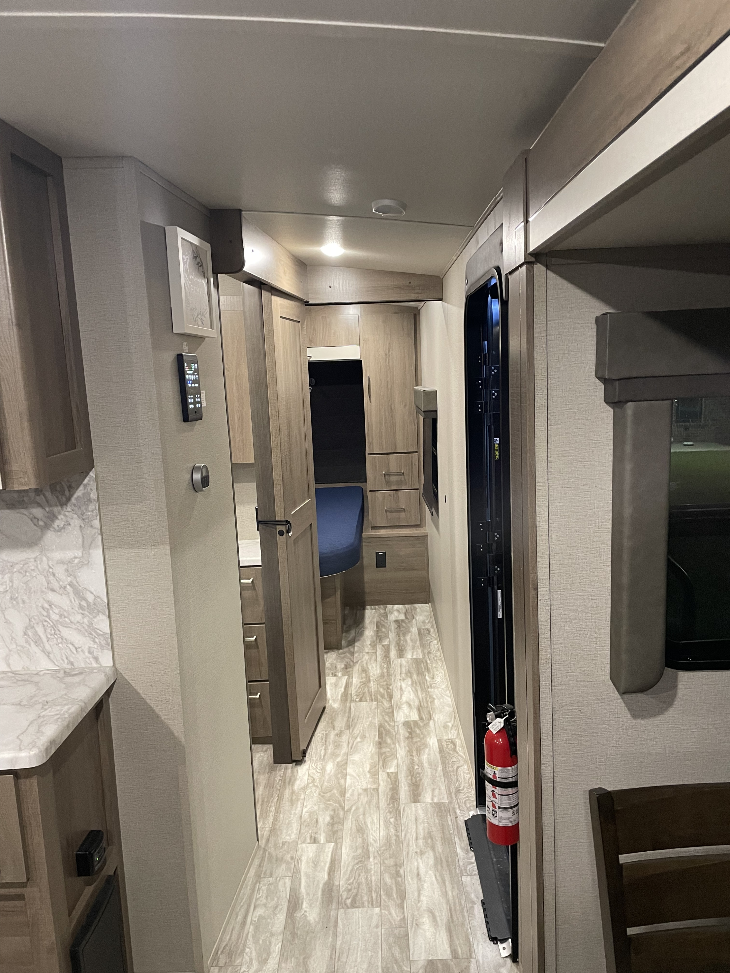 Explore this RV rental's inviting interior: kitchen, bedroom, and safety features like a fire extinguisher.. Grand Design Imagine 2022