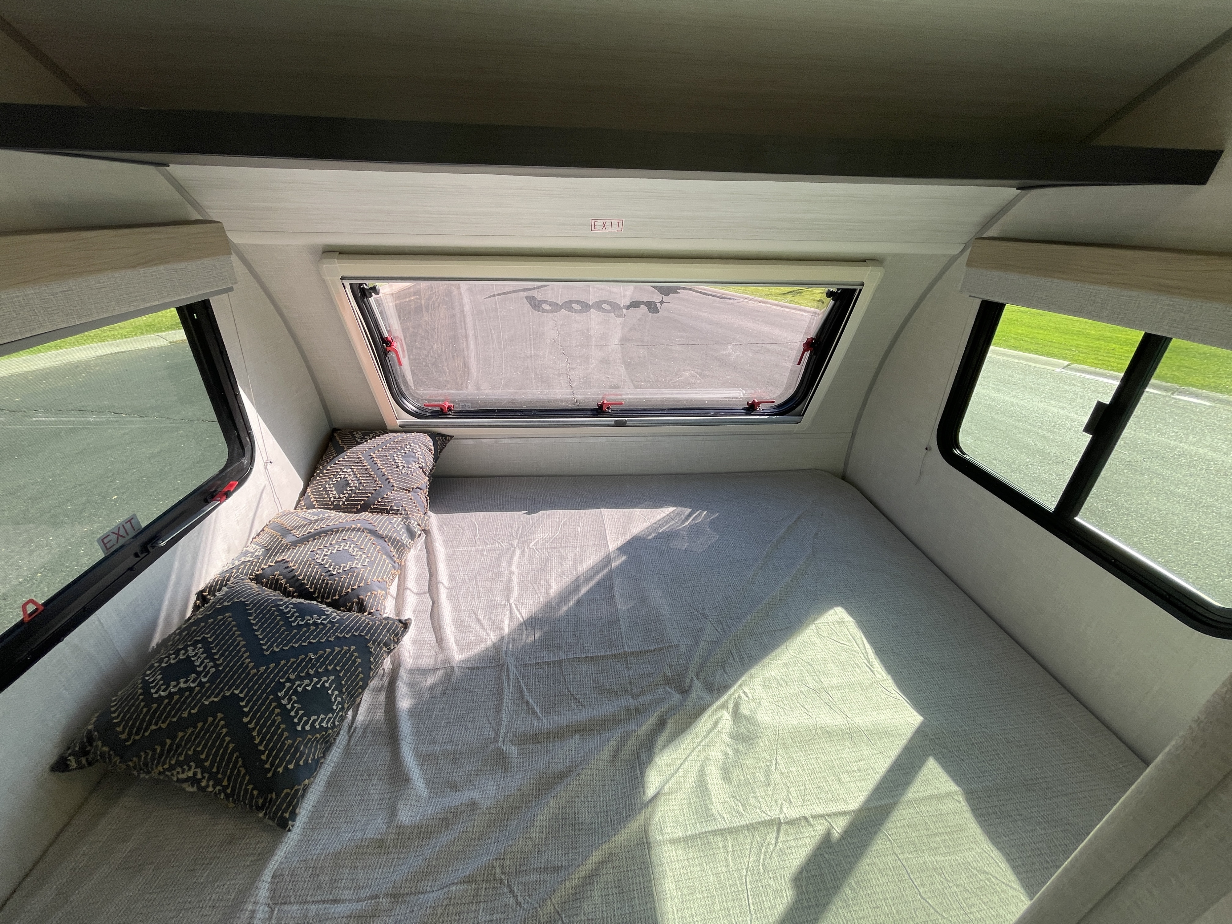 Cozy RV rental interior with a large bed, patterned pillows, and bright windows, ready for your next adventure.. Forest River R-Pod 2023