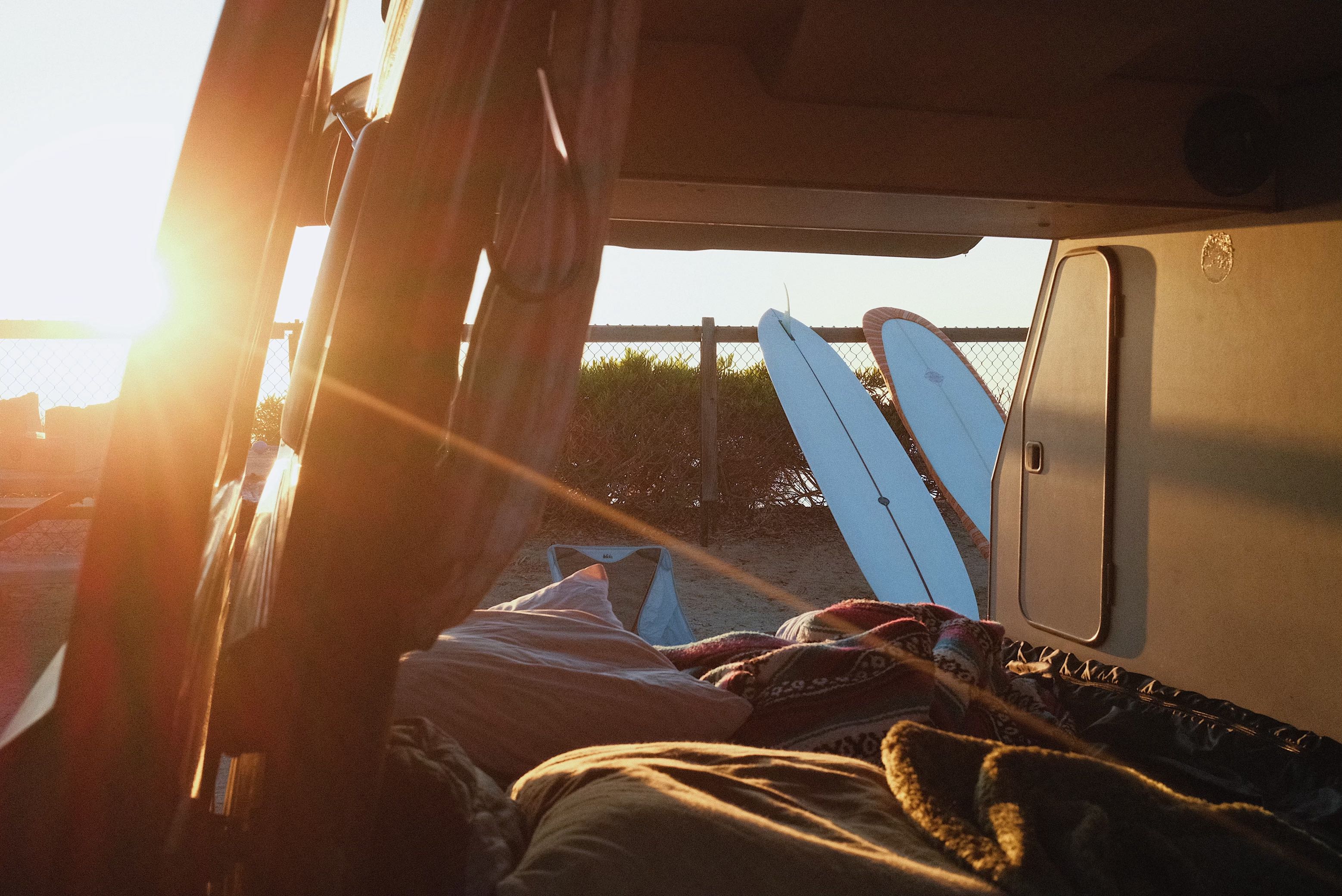 Cozy RV rental view at sunset, with surfboards ready for the waves. Perfect beach camping from inside a van.. Volkswagen Westfalia 1990