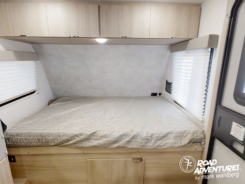 Inside this RV rental bedroom: a comfortable bed with overhead cabinets and side windows, ready for your road adventure.. Winnebago Micro Minnie 2100BH 2023