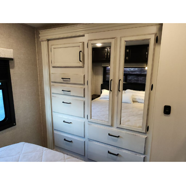 Compact RV rental bedroom with white built-in storage: drawers, cabinets & mirrored closet reflecting the bed. Ideal for travel.. Jayco Redhawk 2023