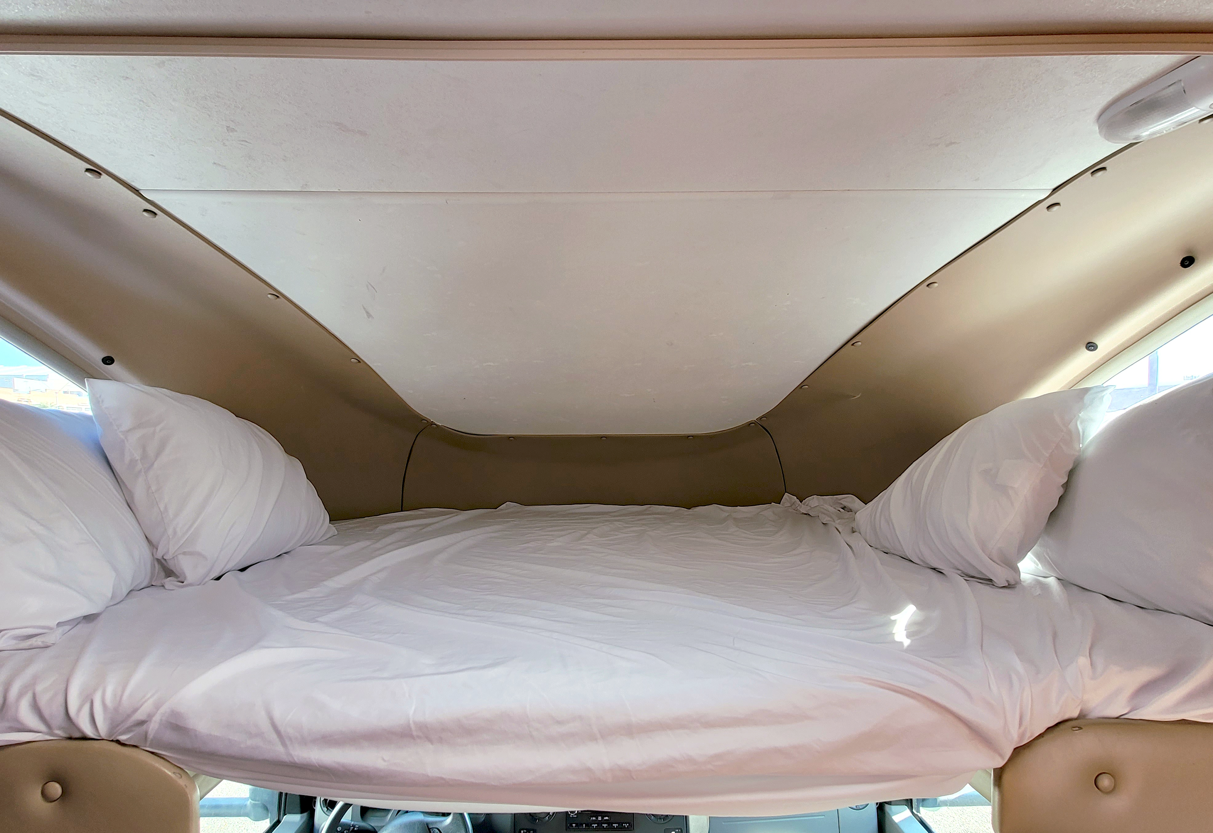 Comfortable overhead sleeping area in an RV rental, featuring white bedding and pillows, designed for a cozy rest.. Thor Motor Coach Majestic Four Winds 19G 2009