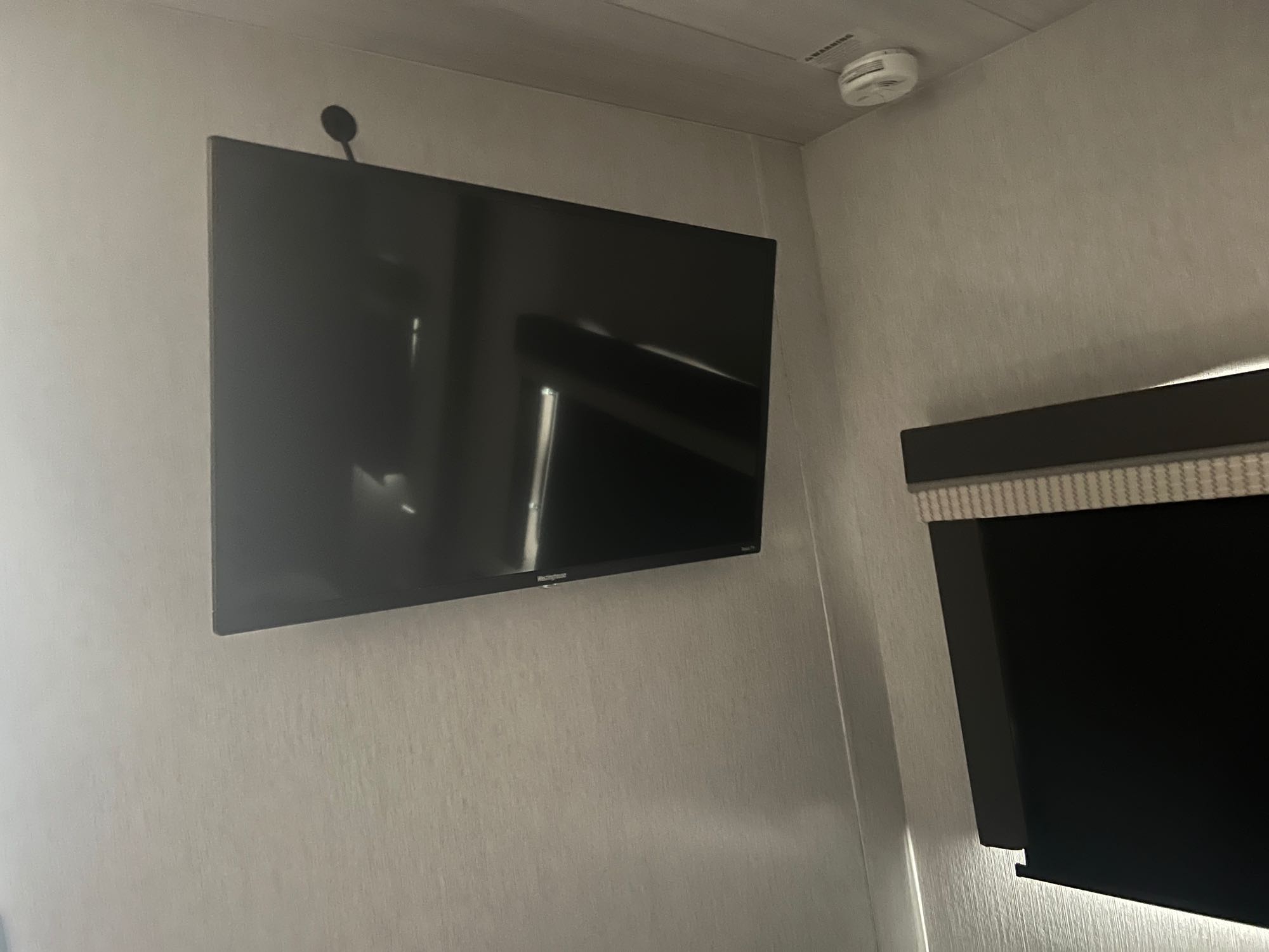 RV rental interior: wall-mounted TV, smoke detector, and another screen below.. Forest River Salem 2022
