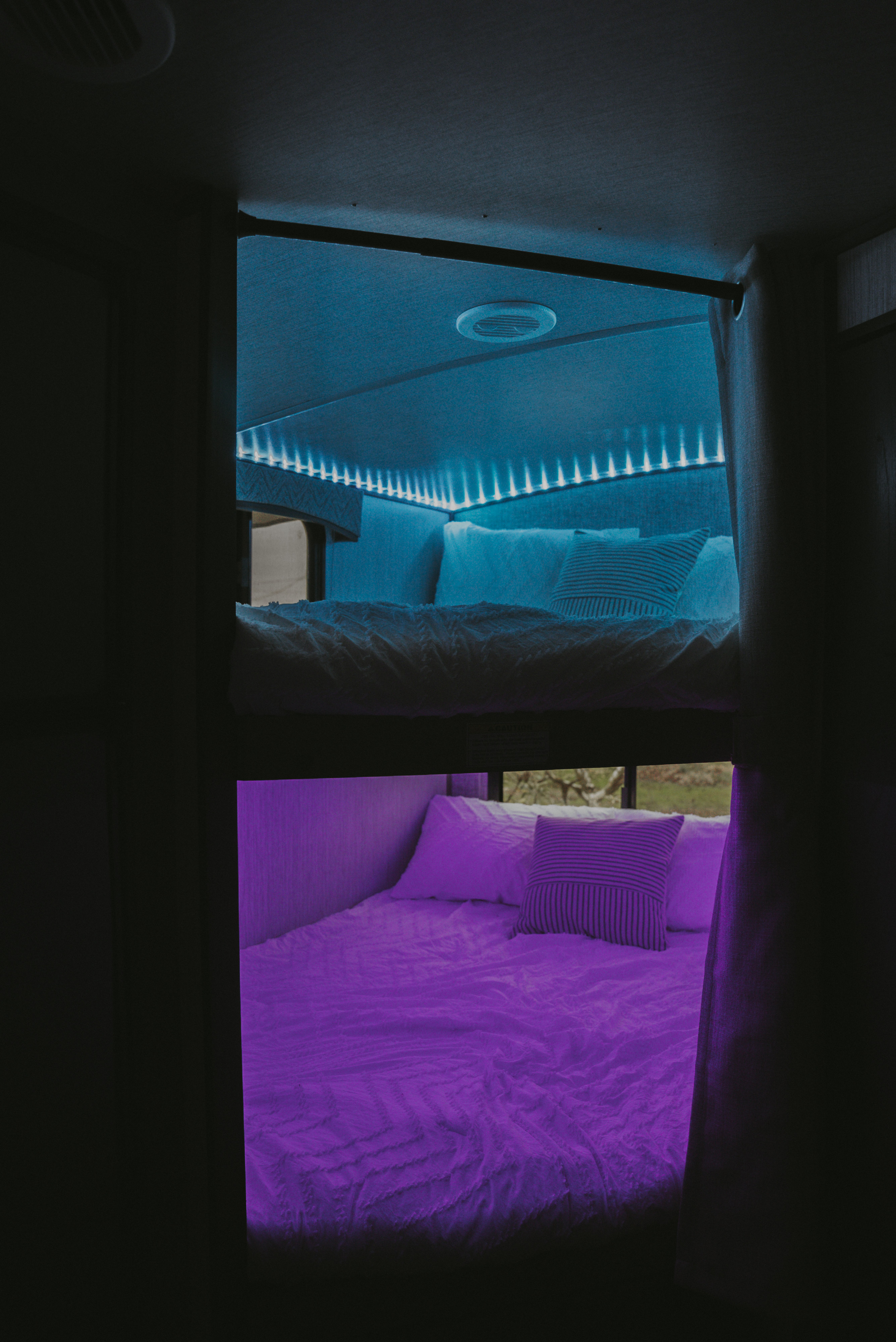 Cozy RV rental bunk beds feature vibrant blue and purple LED lighting, offering a comfortable, colorful sleeping area.. Heartland RVs Sundance Ultra Lite 2021