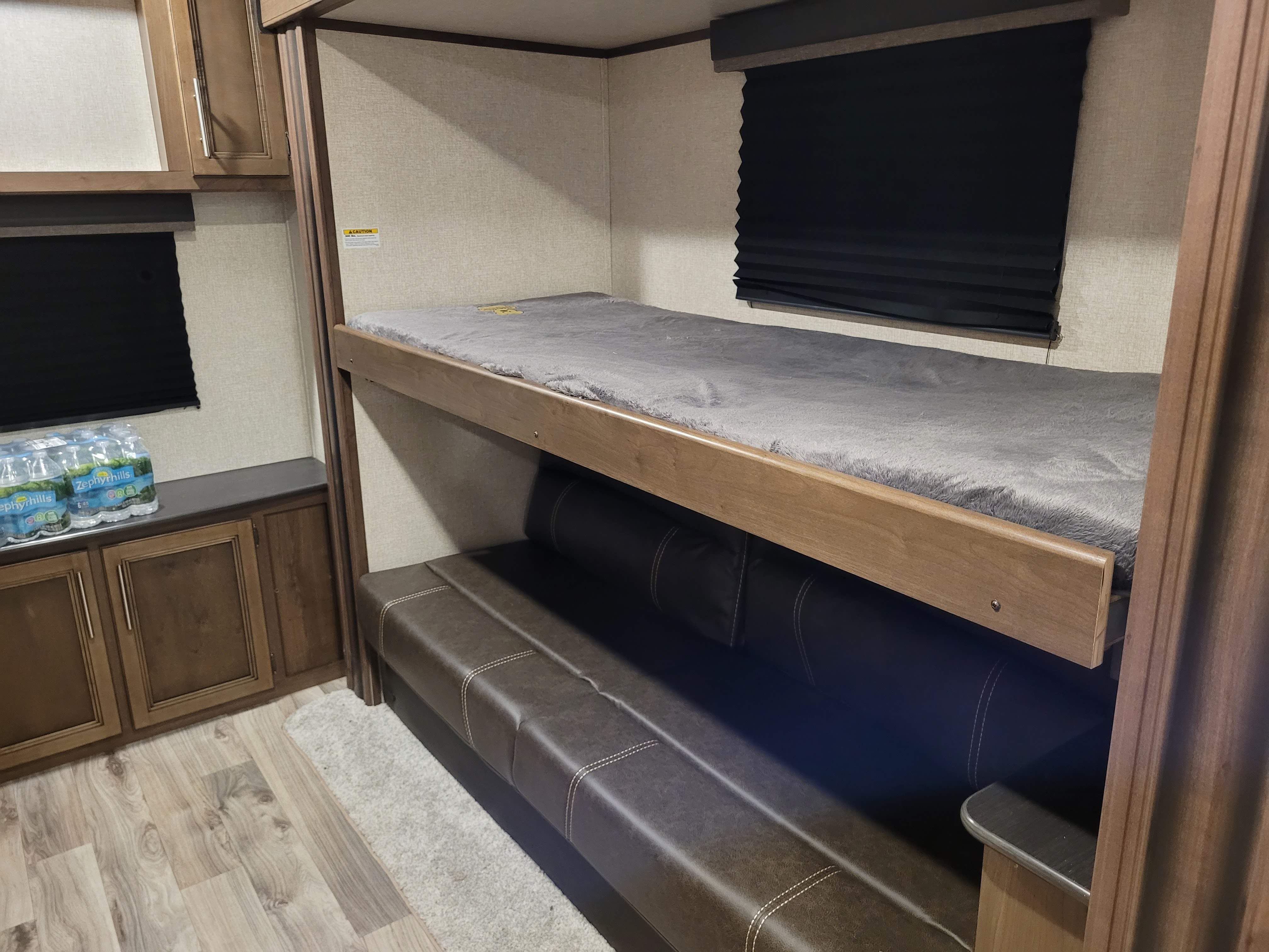 RV rental bunk beds. This cozy camper features a top bunk with grey bedding and a lower convertible sofa/bed, plus storage.. Keystone RV Cougar 2020