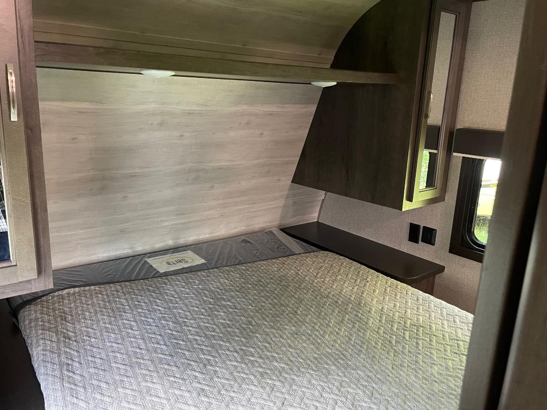 Inside an RV rental: a cozy bedroom with a Serta mattress, built-in storage, and window for travel comfort.. Jayco Jay Flight SLX 2022