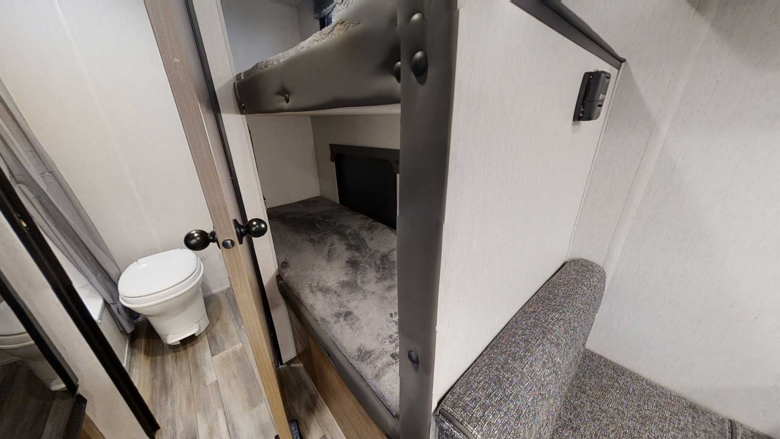 Inside this **rv rental**: convenient bunk beds, a compact toilet area, and cozy seating for your mobile adventures.. Forest River Wolf 17' Bunkhouse 2026