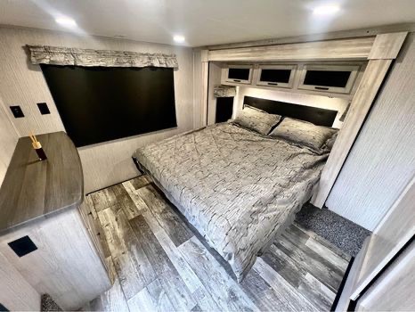This cozy RV rental bedroom offers a comfortable bed, modern finishes, and smart storage, ideal for your next trip.. Forest River Sandpiper 2022