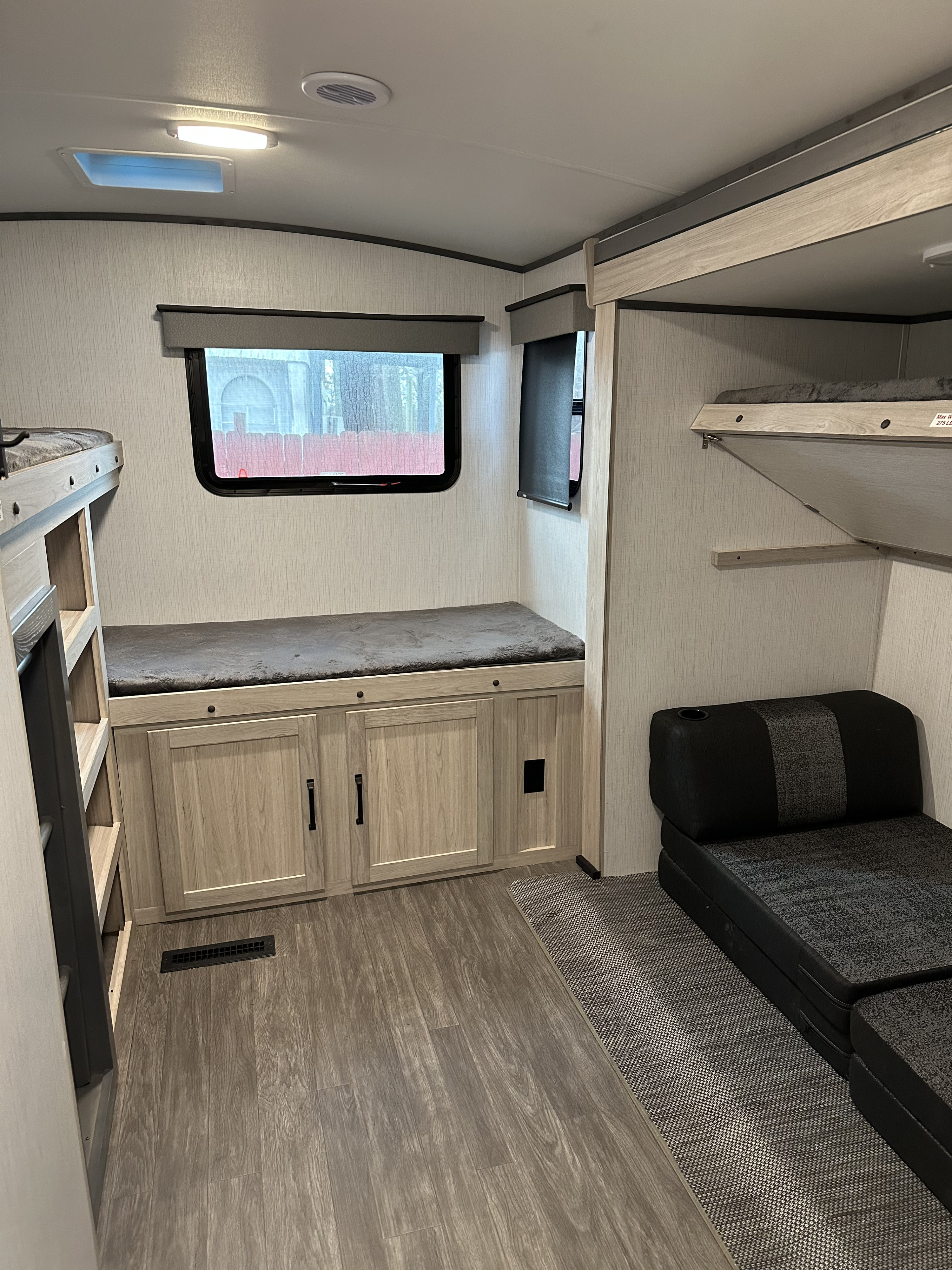 An RV rental's versatile interior showing bunk beds, a window bench, and a convertible sofa/bed on vinyl flooring.. Twilight RVS Signature 2022