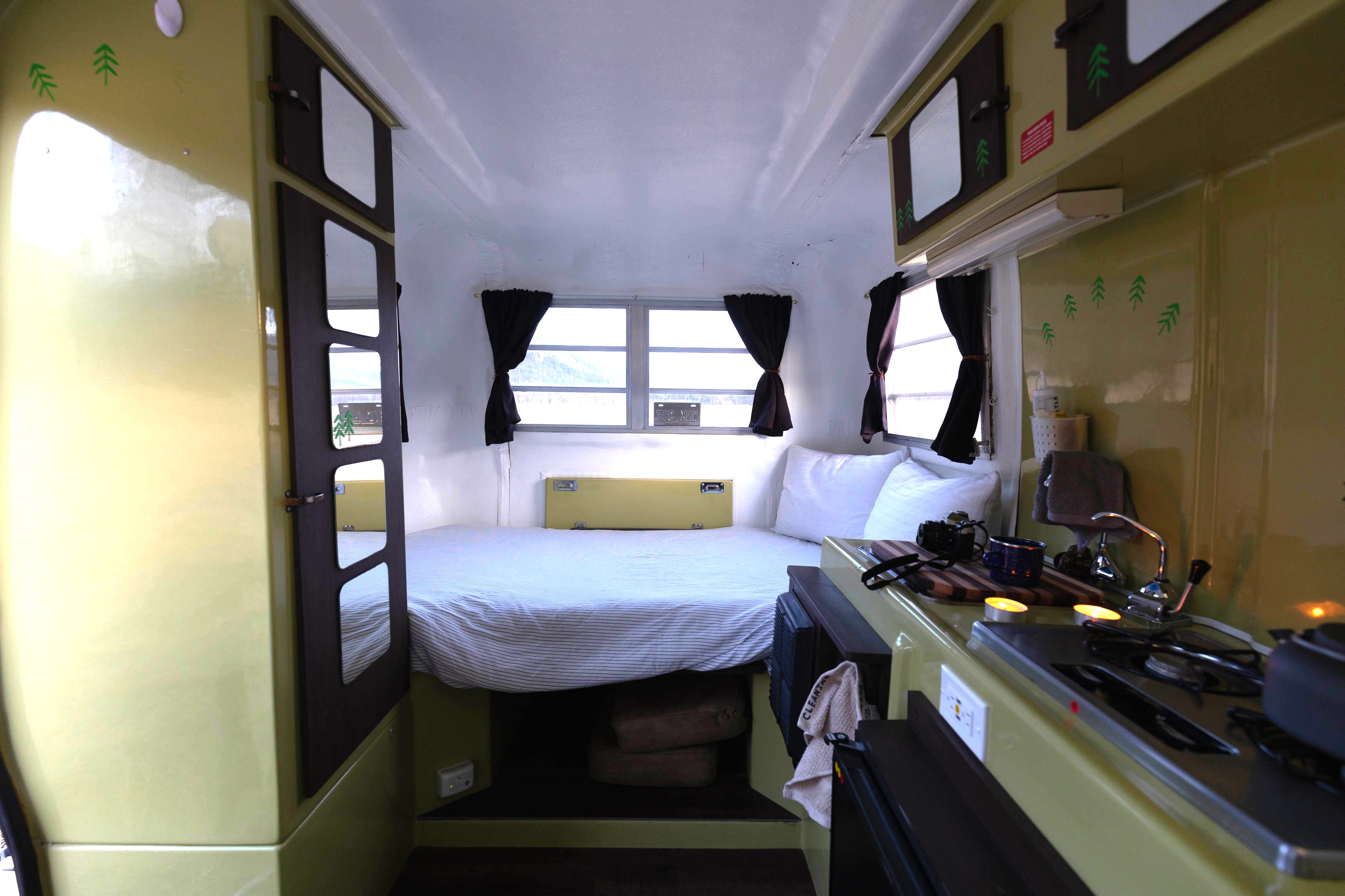 Cozy rv rental interior: A bed, bright windows, and a compact kitchenette with stove and sink.. Trillium Rv 1300 1976